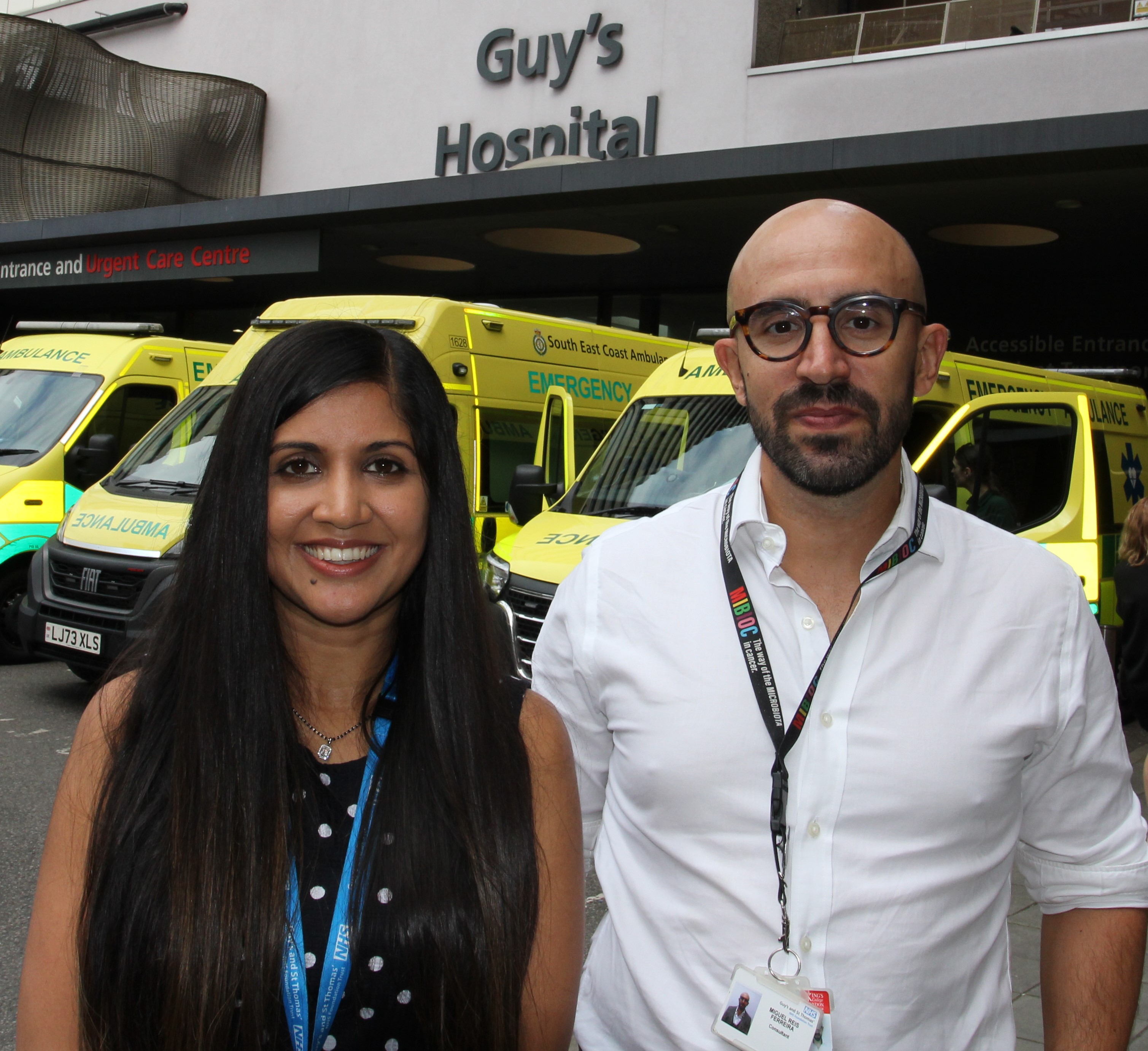 Dr Anjali Chander and Dr Miguel Reis Ferreira in front of a line of ambulances outside Guy’s and St Thomas’ NHS Foundation Trust