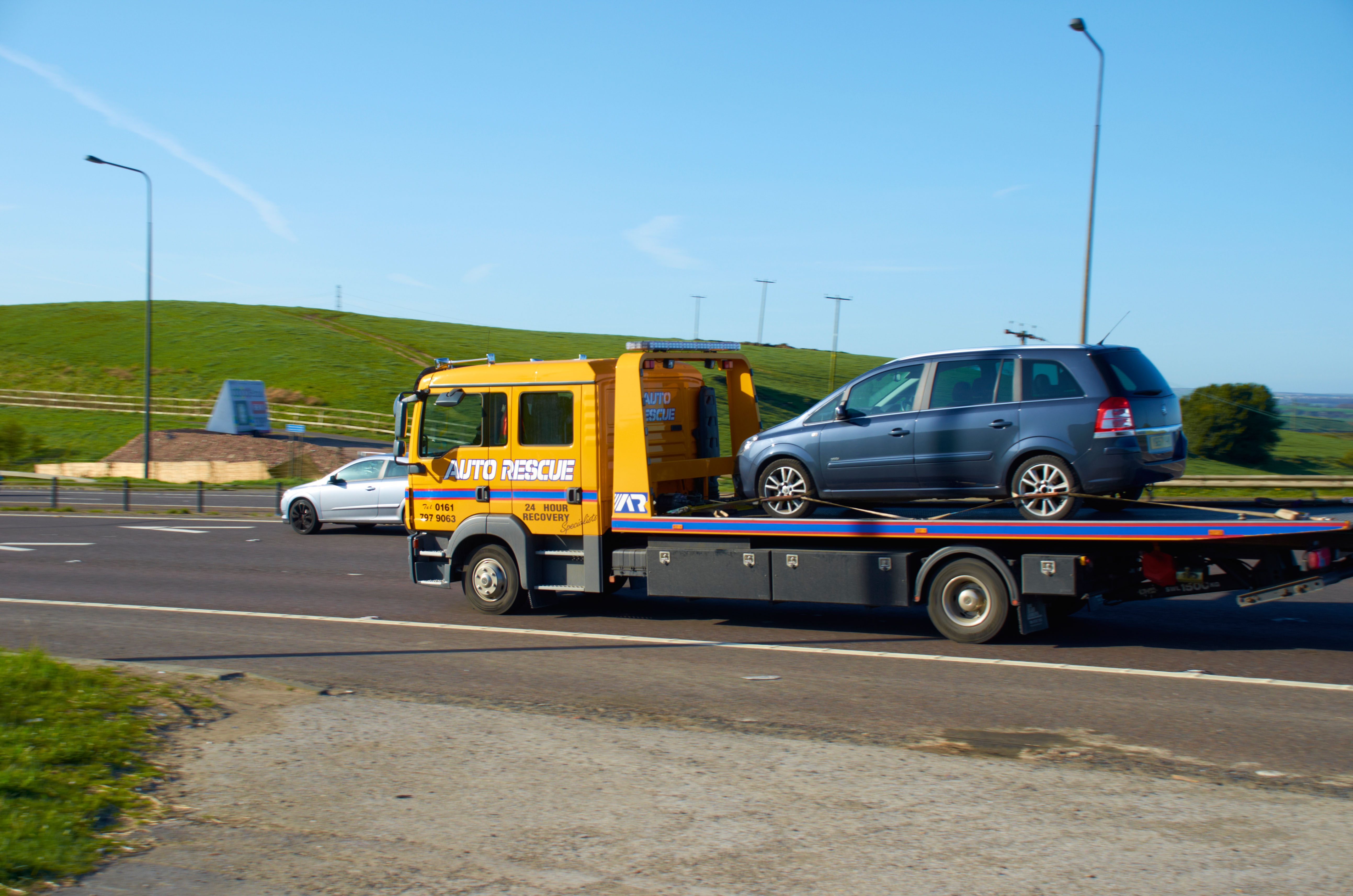 A broken down car on a flatbed truck