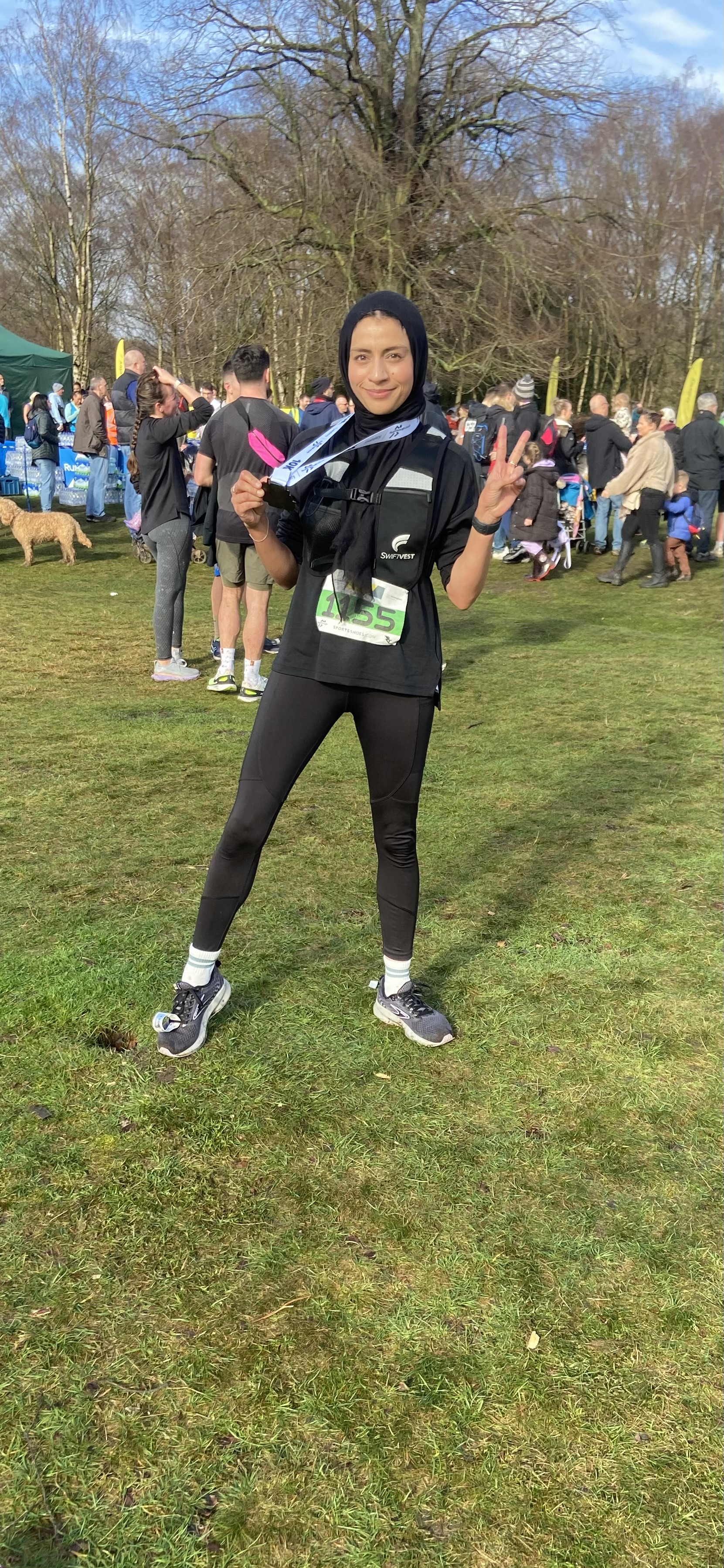 Tanzeela Khalid wearing black leggings, a black T-shirt and a black hijab with a medal round her neck from a running event