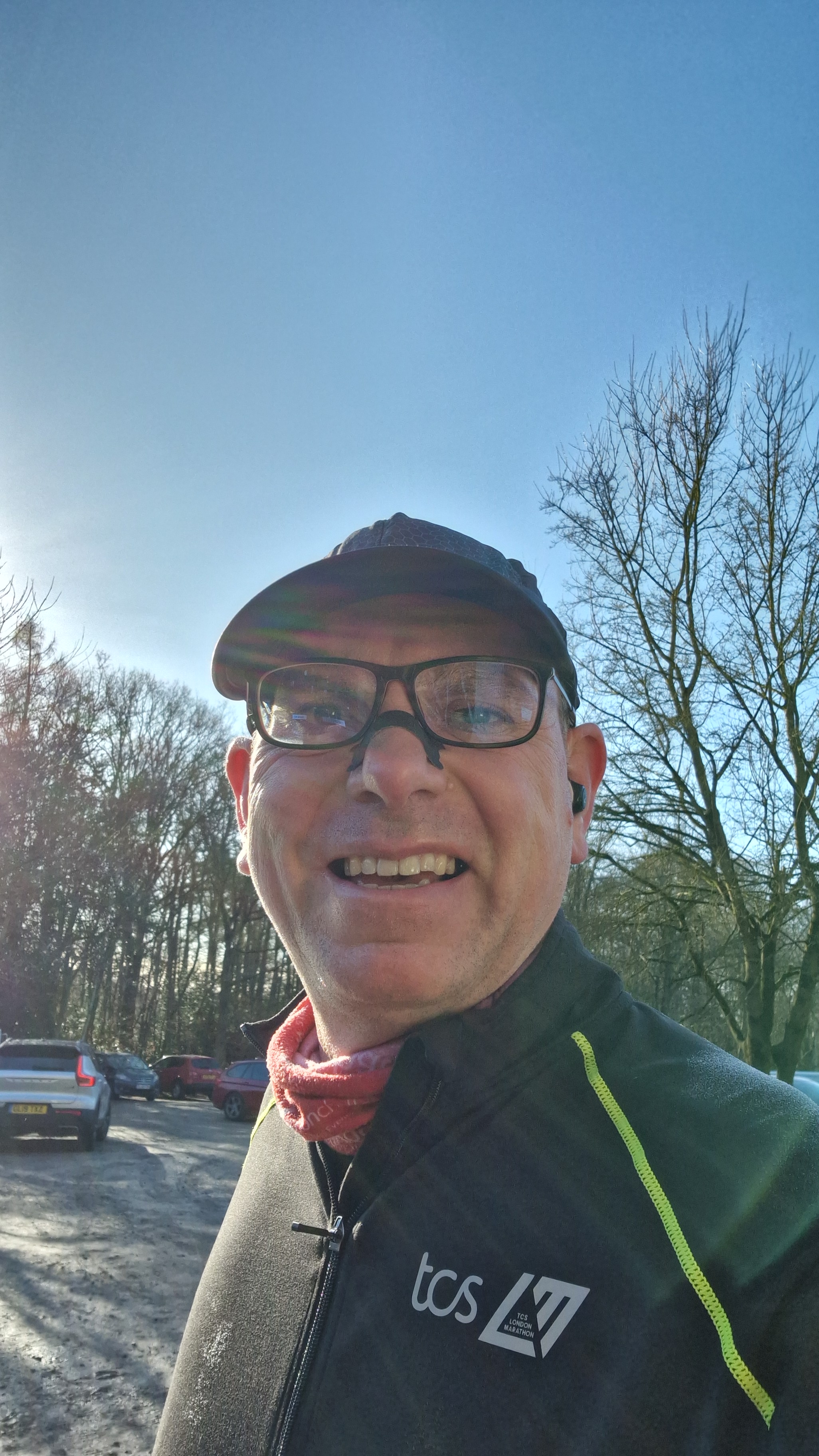Graham Cooksey smiling wearing glasses, a cap and a TCS running top