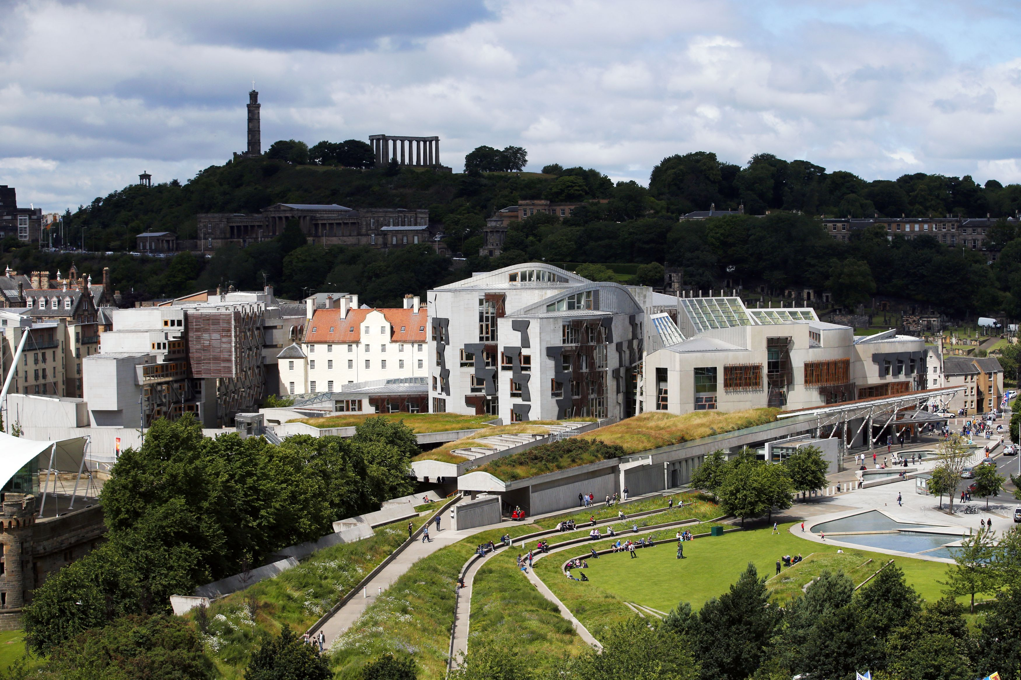 Exterior view of the Scottish Parliament building, with Calton Hill beyond