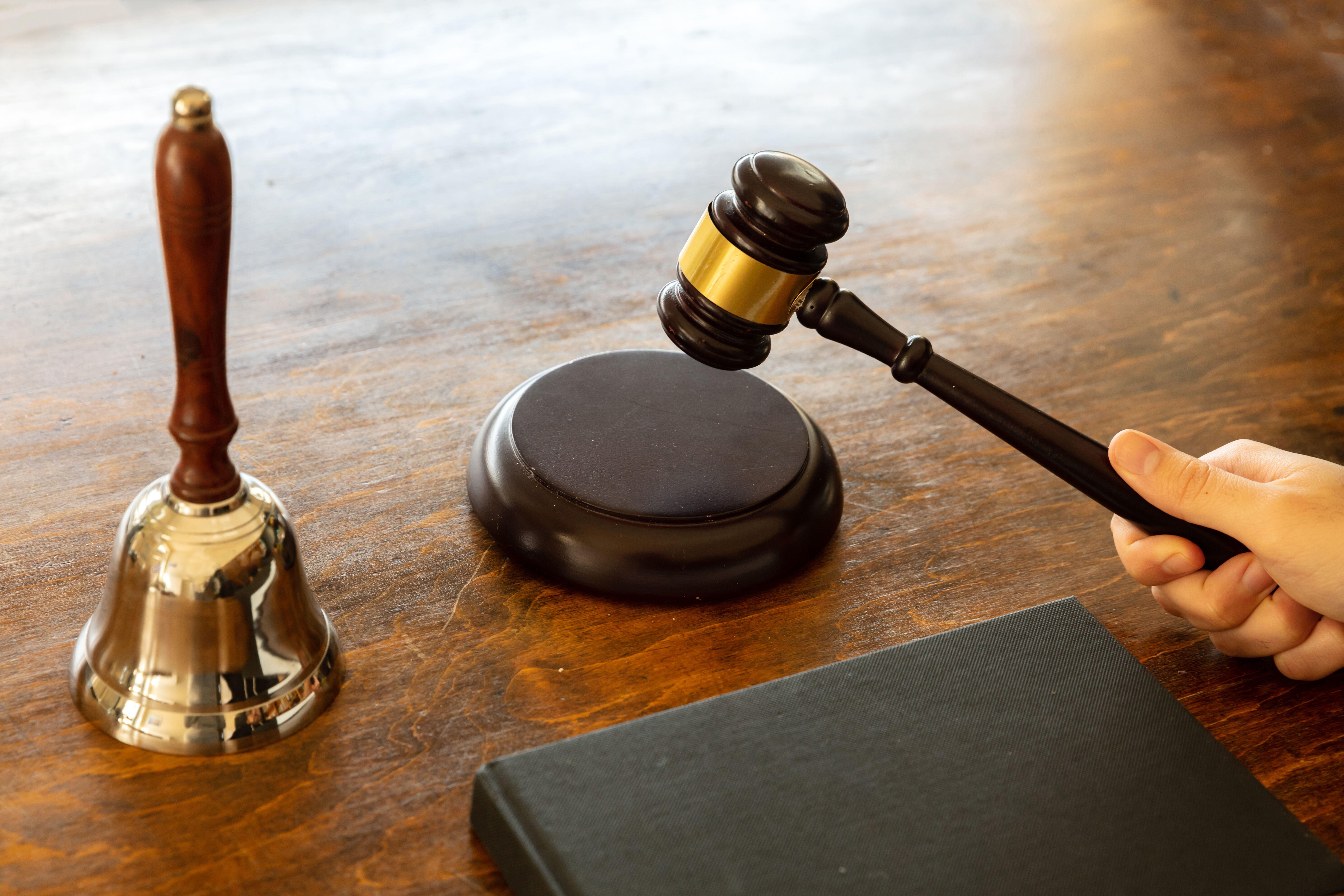 Judge holding a gavel on wooden courthouse desk background. Law theme.