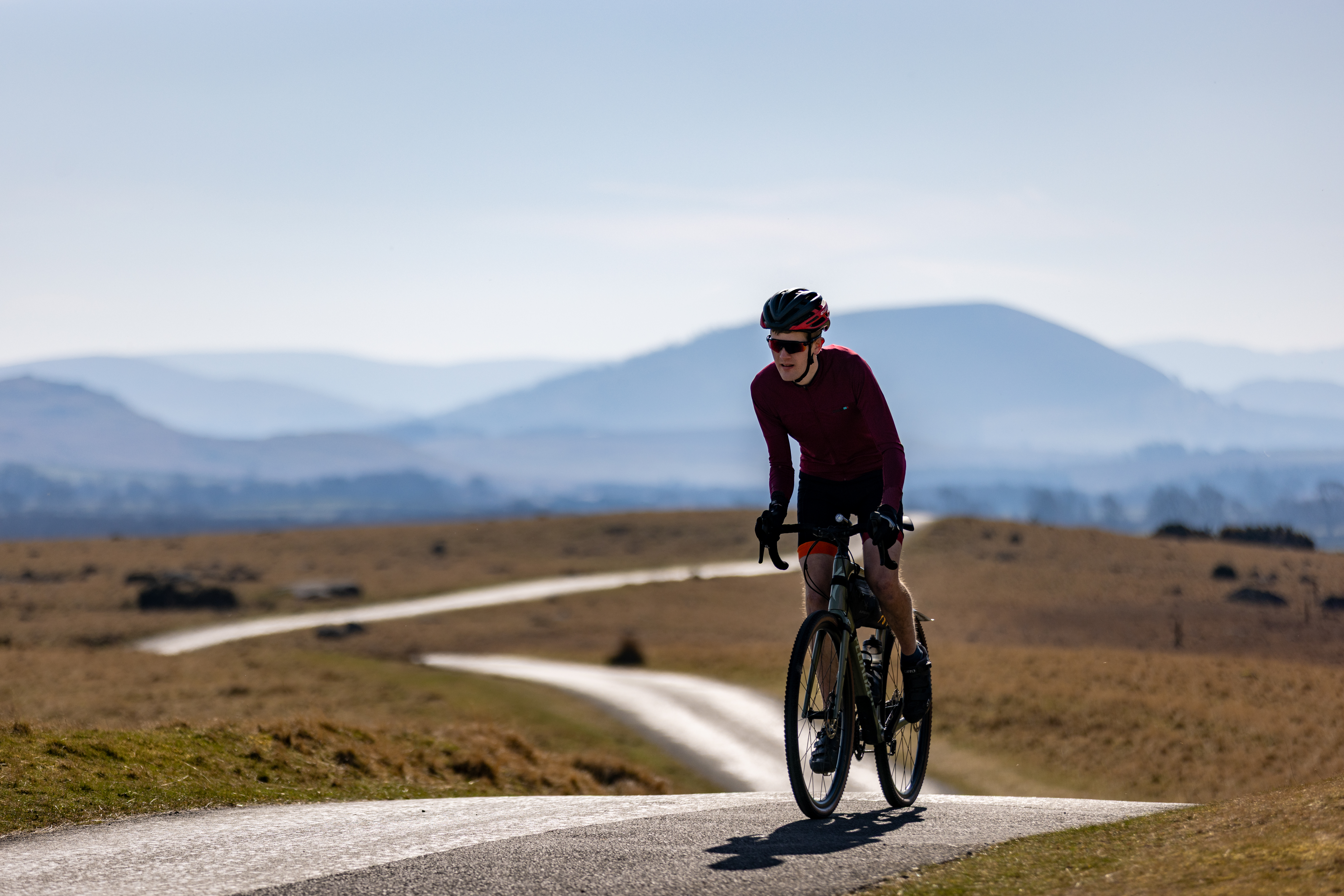 Man wide camera shot of a man cycling across vast terrain