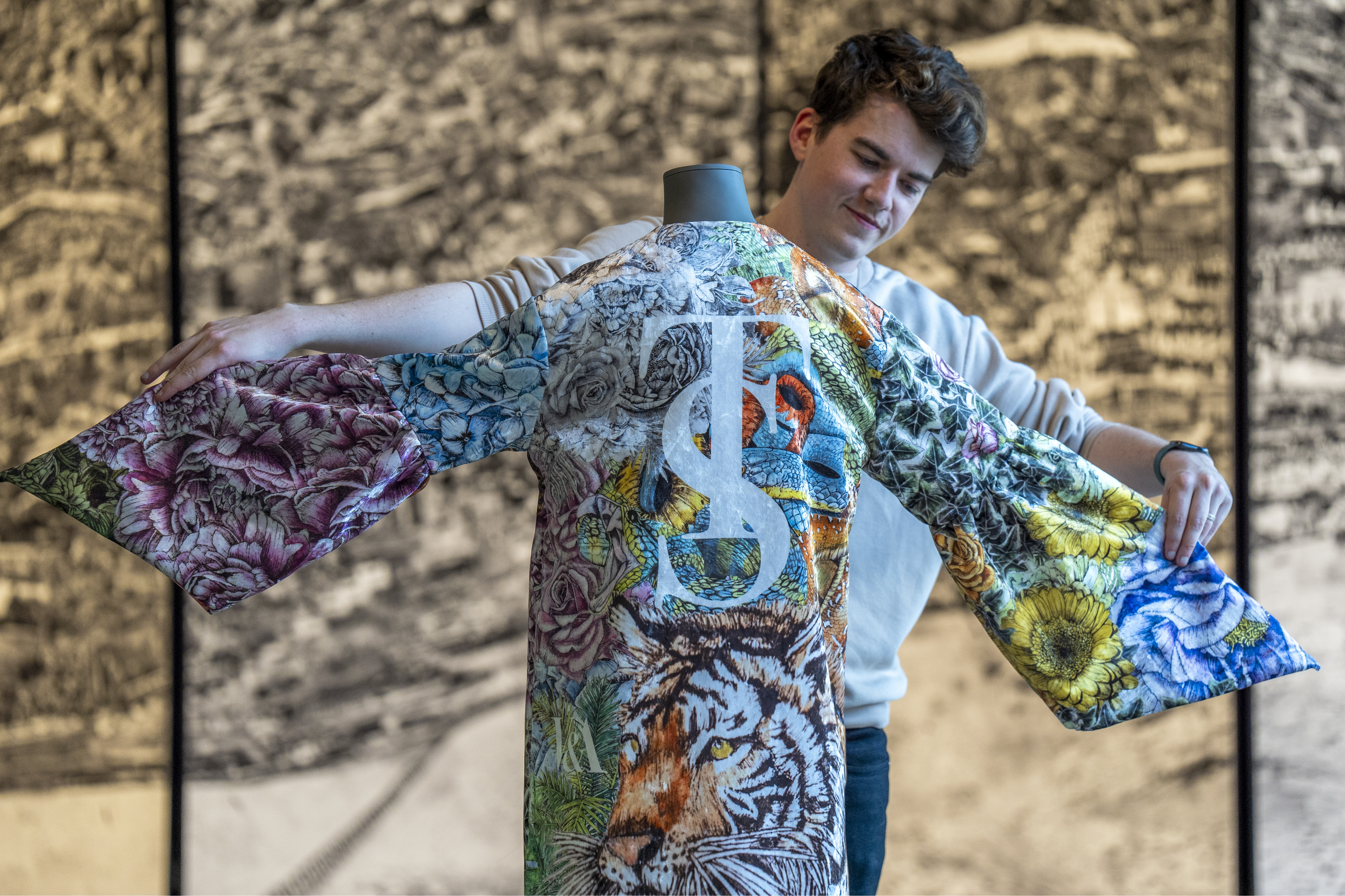 A man adjusts a colourful kimono on a display stand
