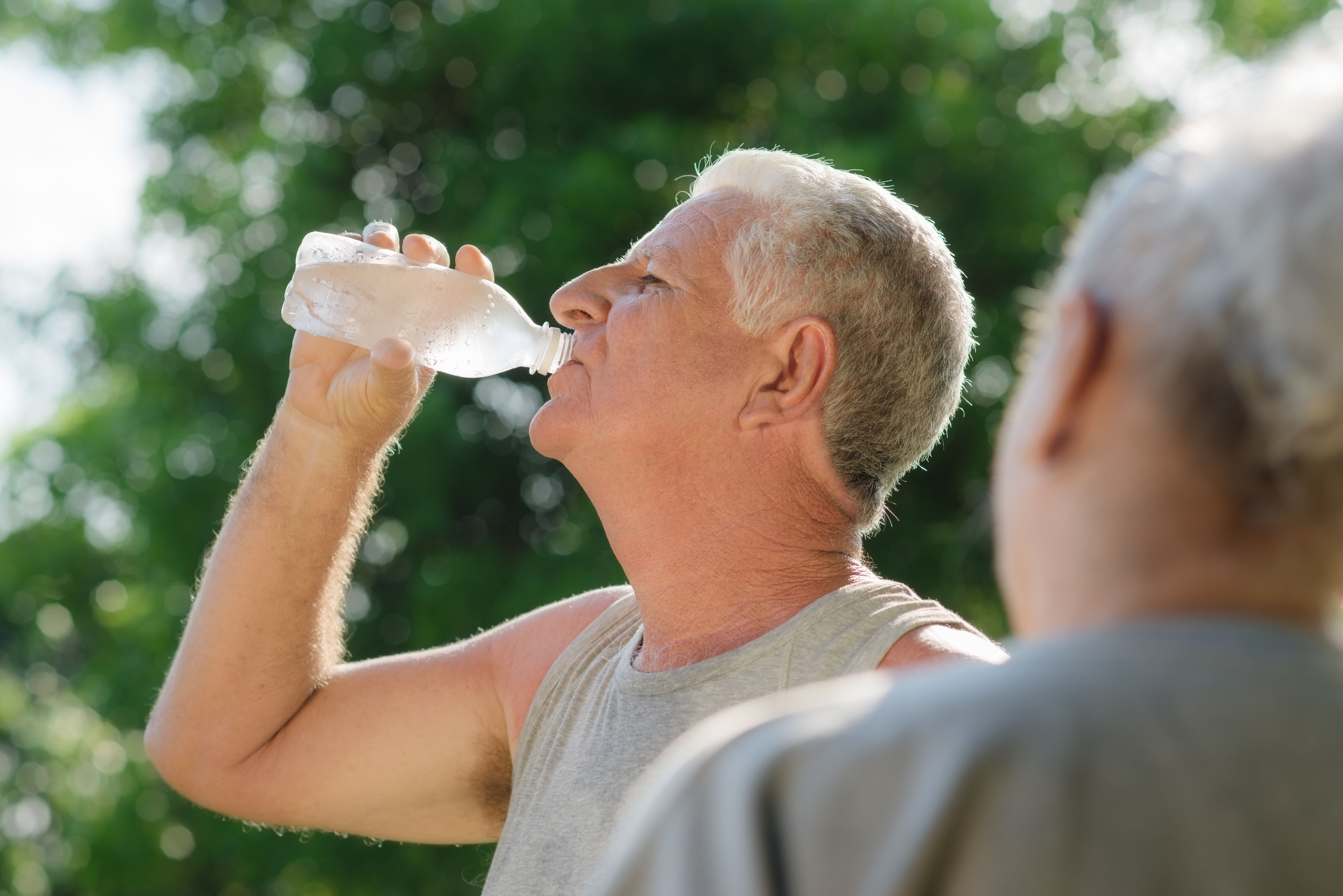 Old man drinking a bottle of water in a park