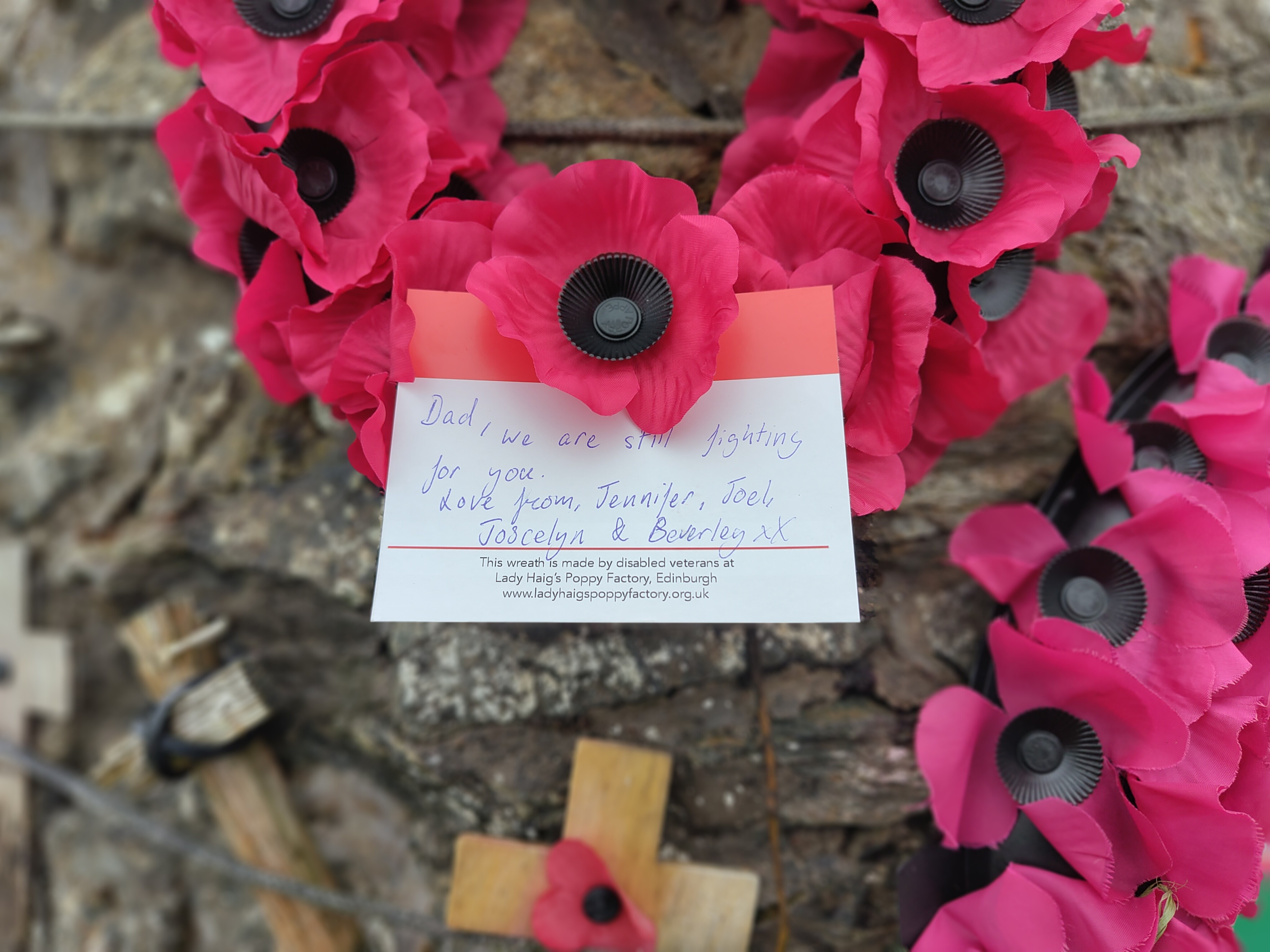 A wreath with a note attached to it left at the cairn