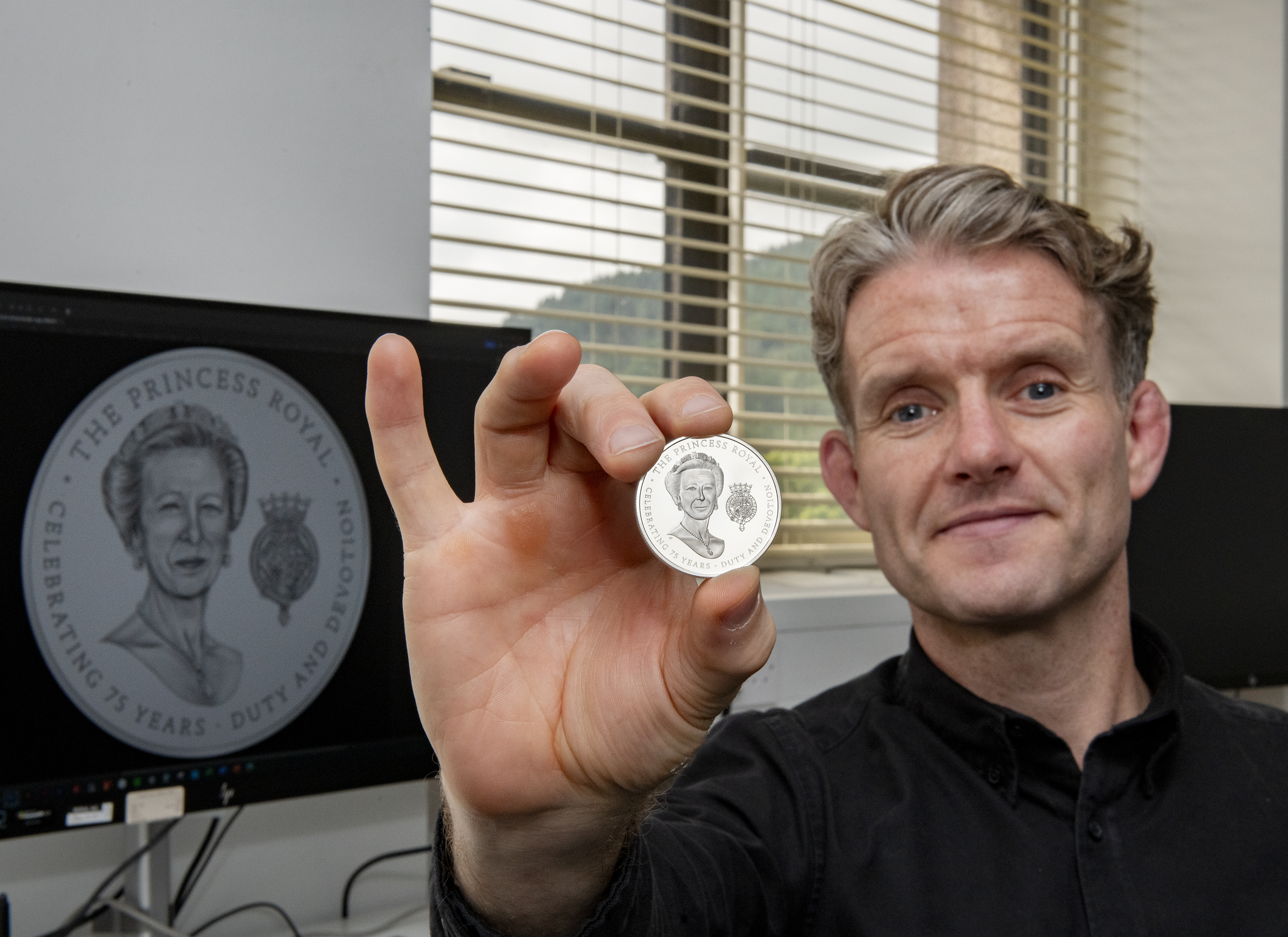 Royal Mint coin designer Thomas T Docherty holding the coin featuring the princess