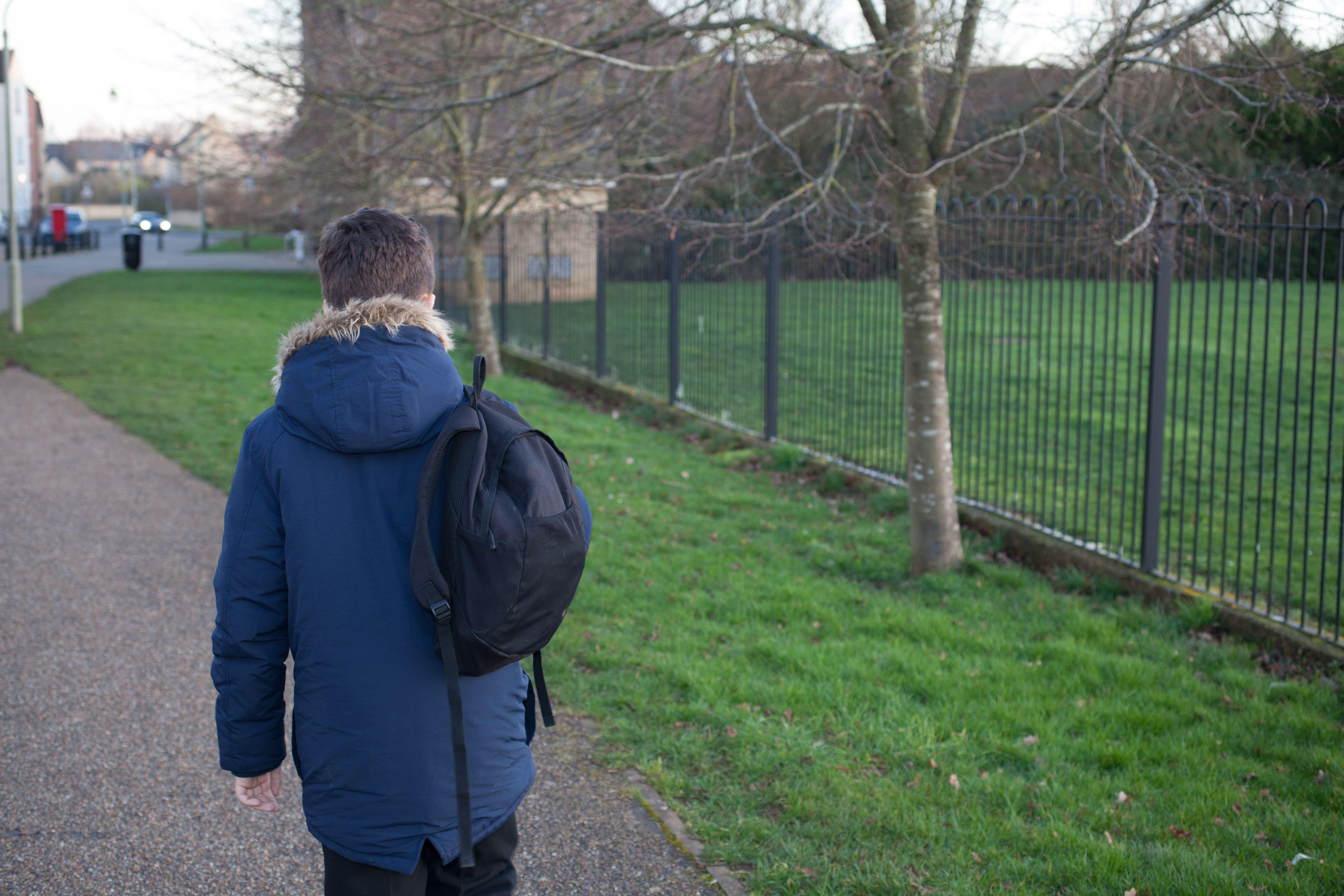 A school boy walking home outside his school