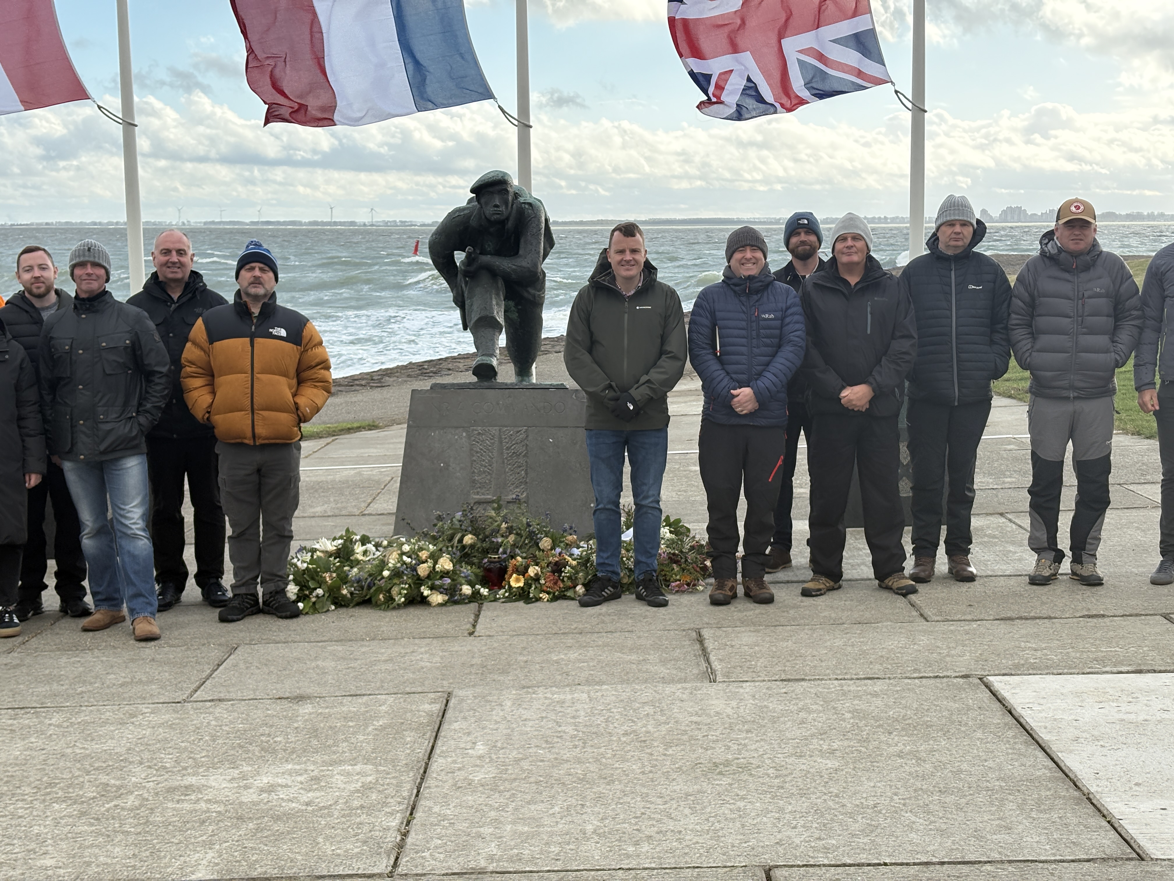 A group of people posing for a photo at a war memorial by the sea