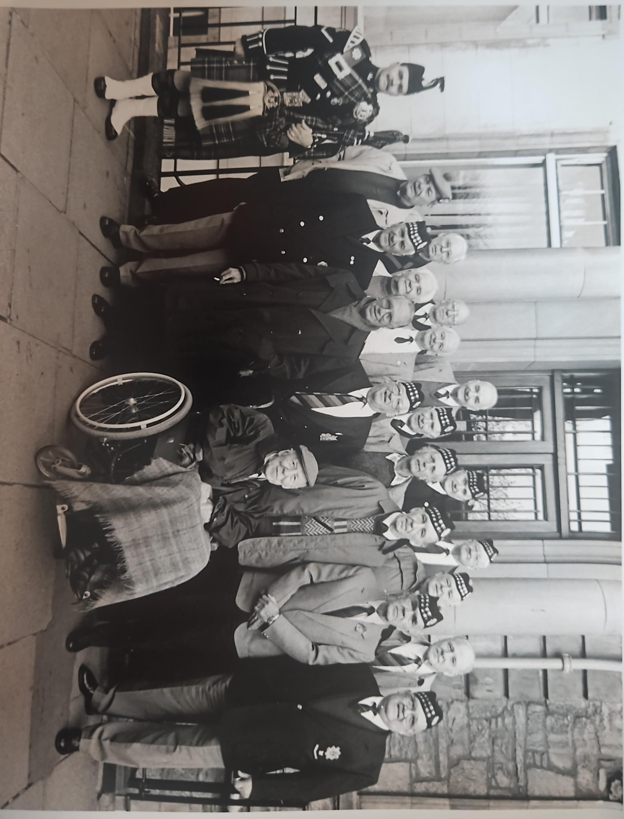 Black and white photo of military veterans posing for a photo outside a building