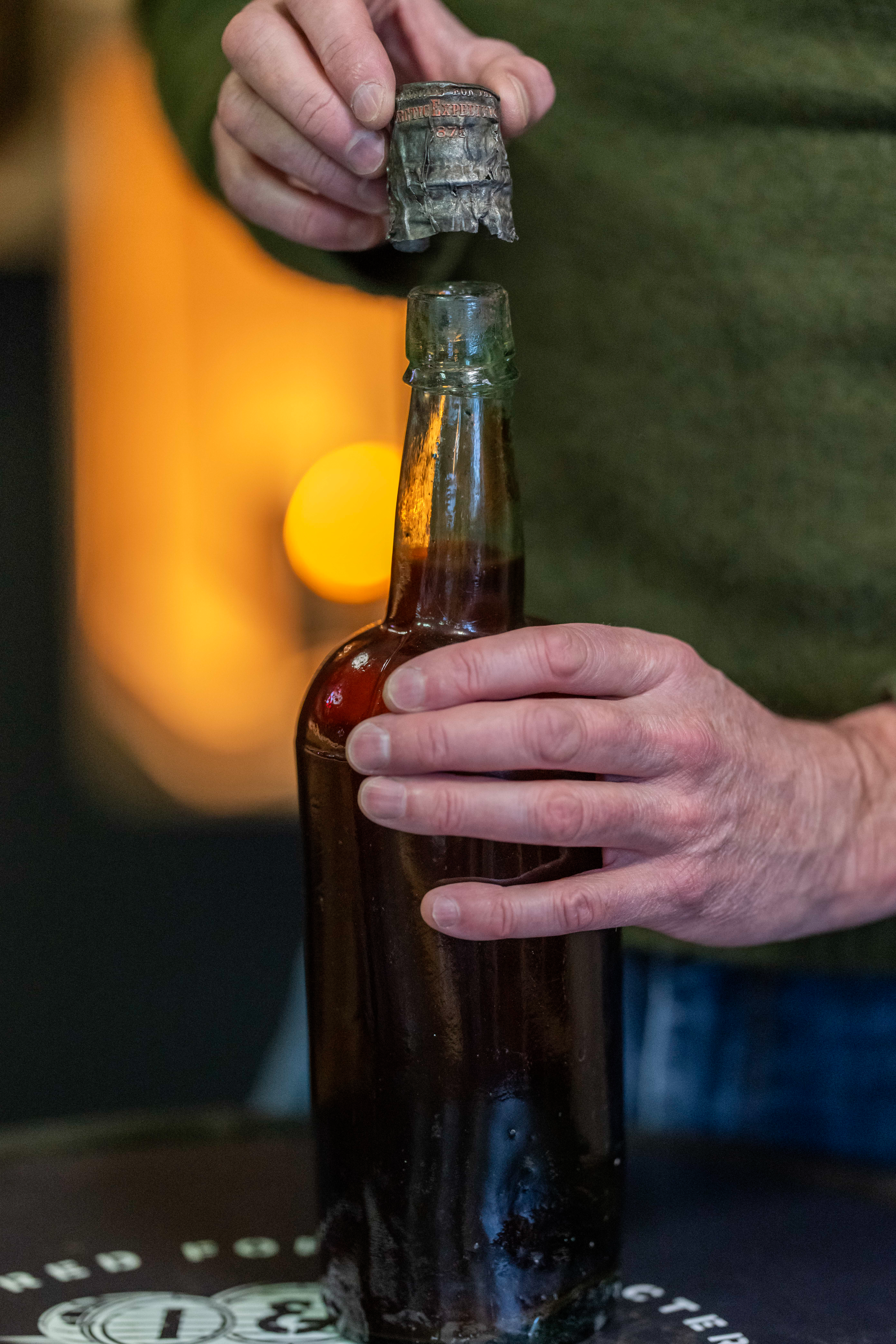 A top is lifted off a bottle of beer