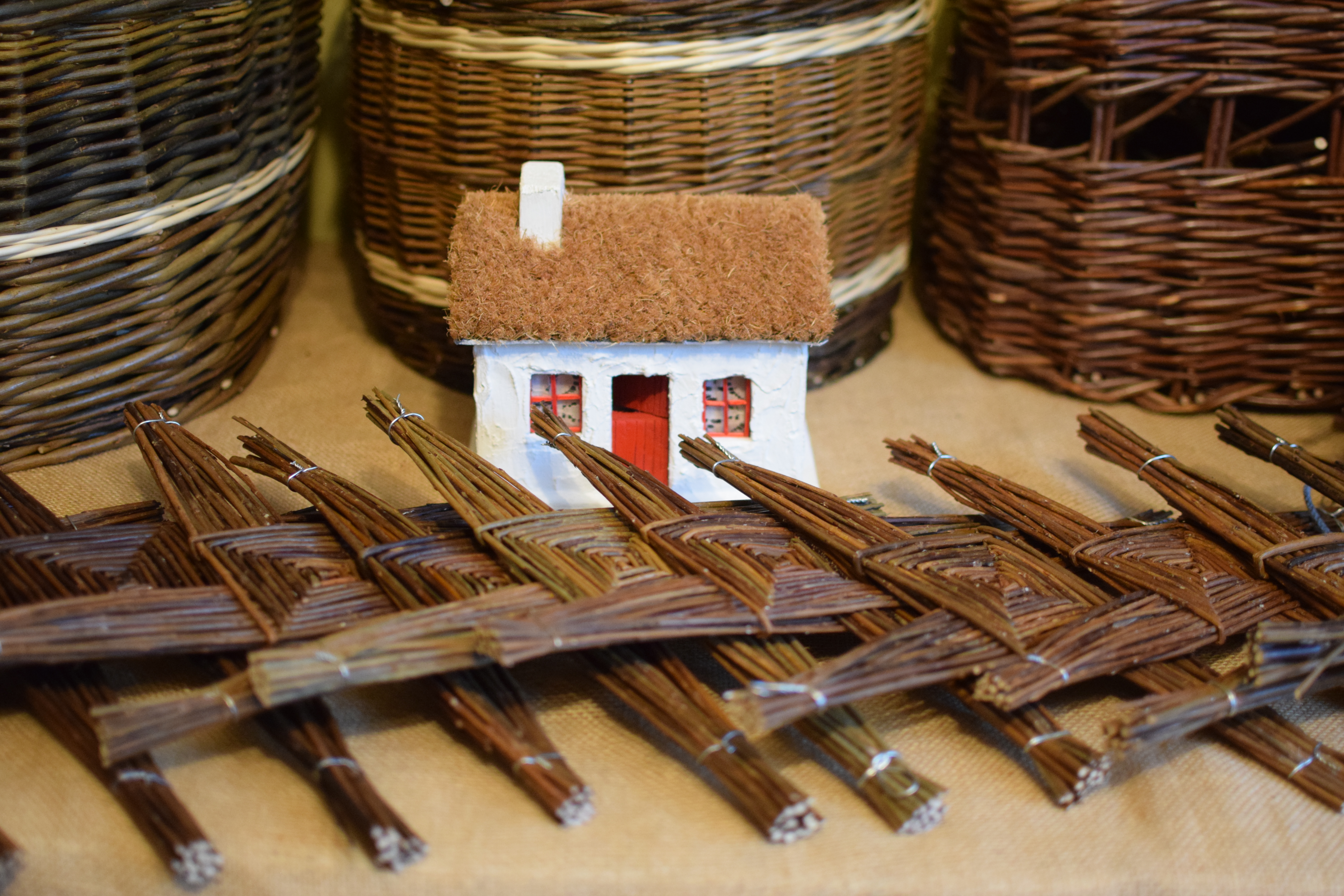 A small model house sitting among weaved items