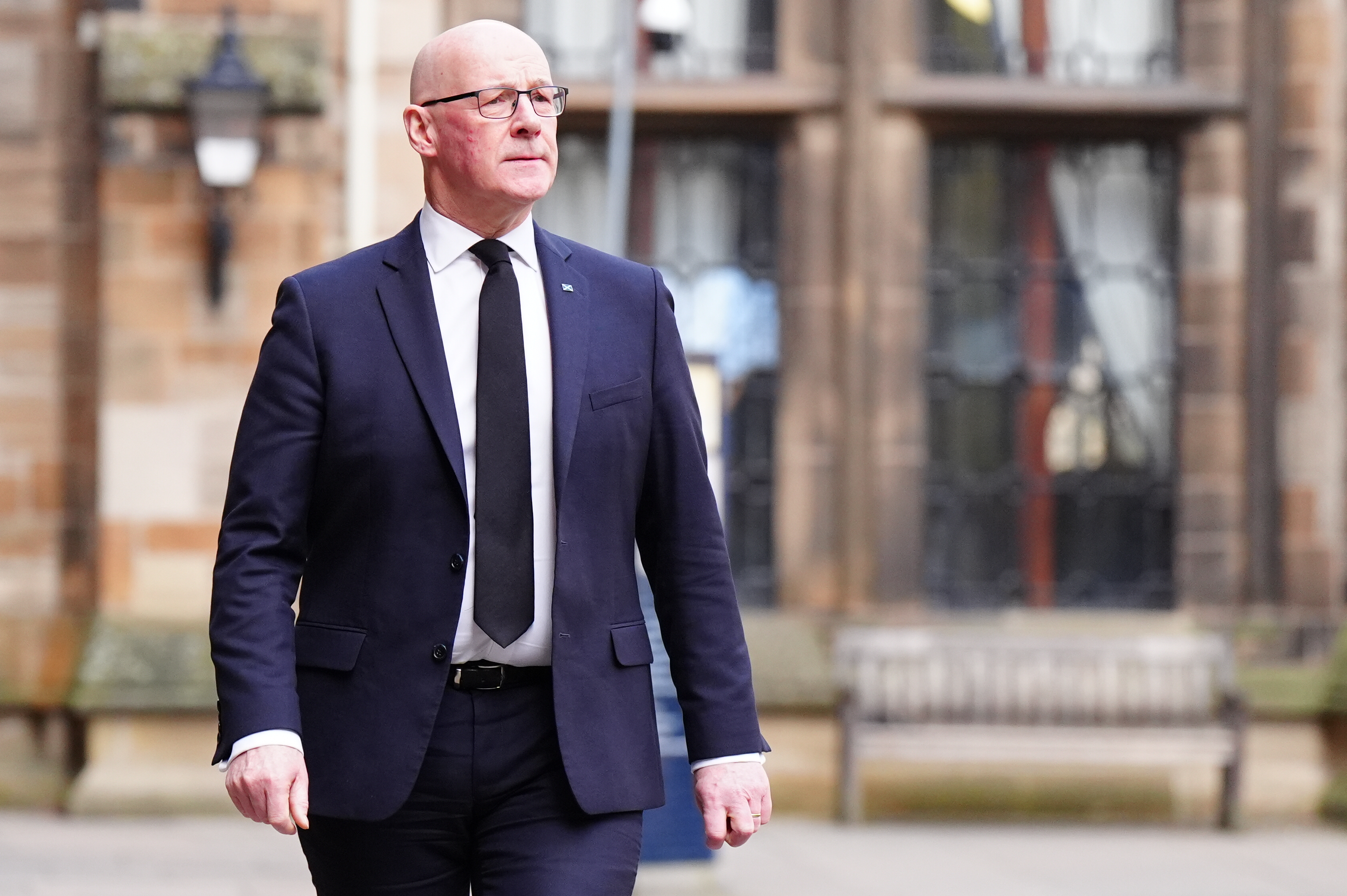 Scottish First Minister John Swinney walking along a street