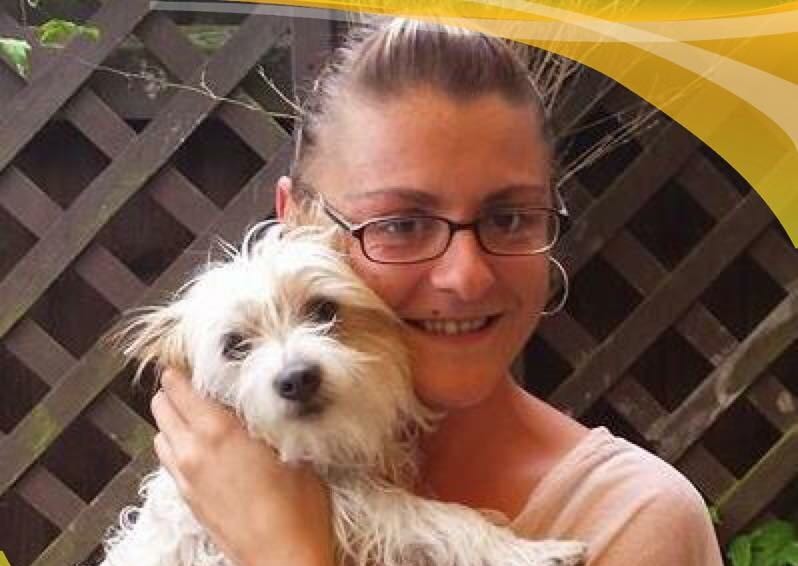 Handout photo of LIsa Holland smiling, while cuddling a small white dog against her face