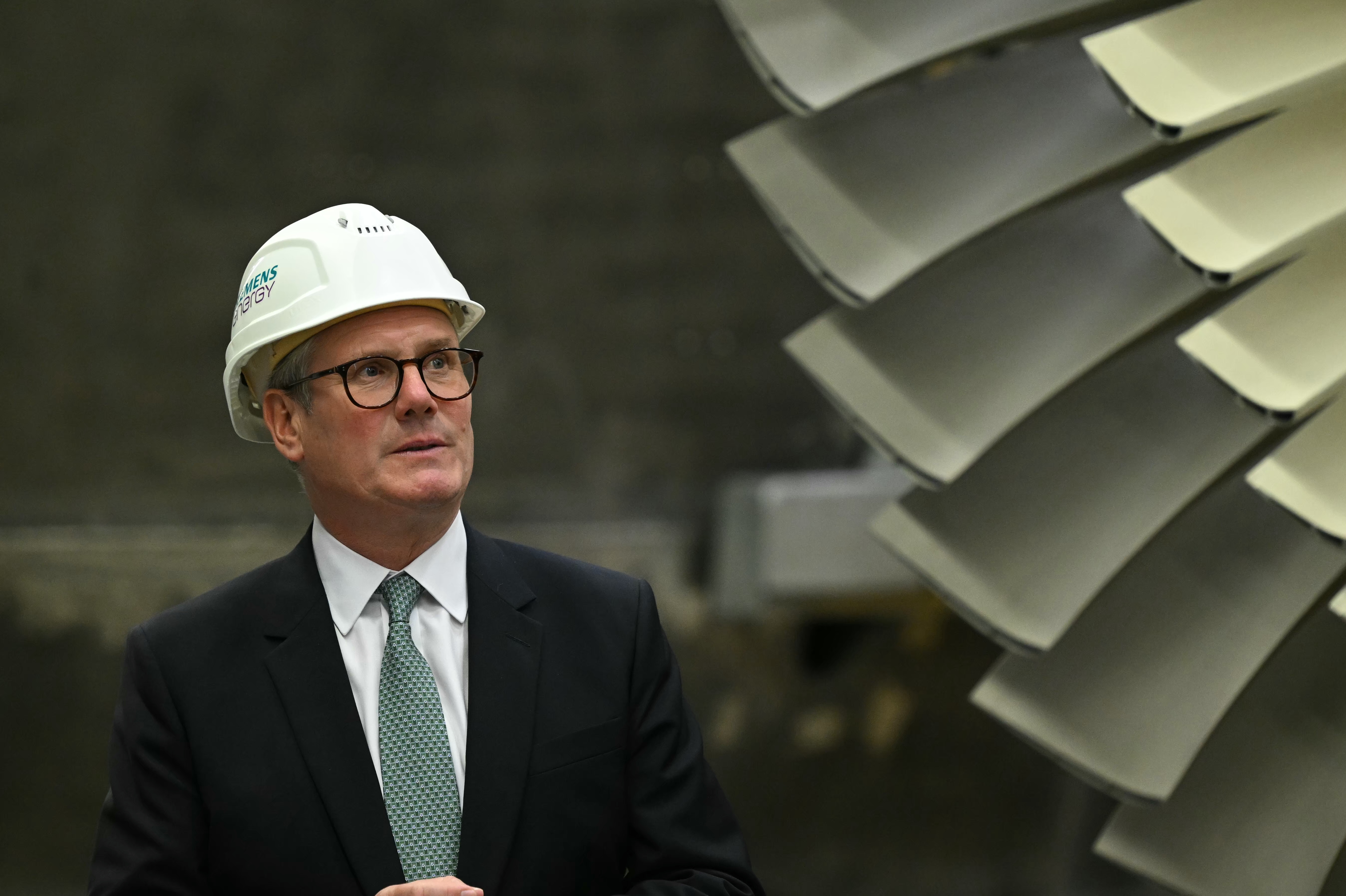 Sir Keir Starmer in white hard hat, standing next to a large fan