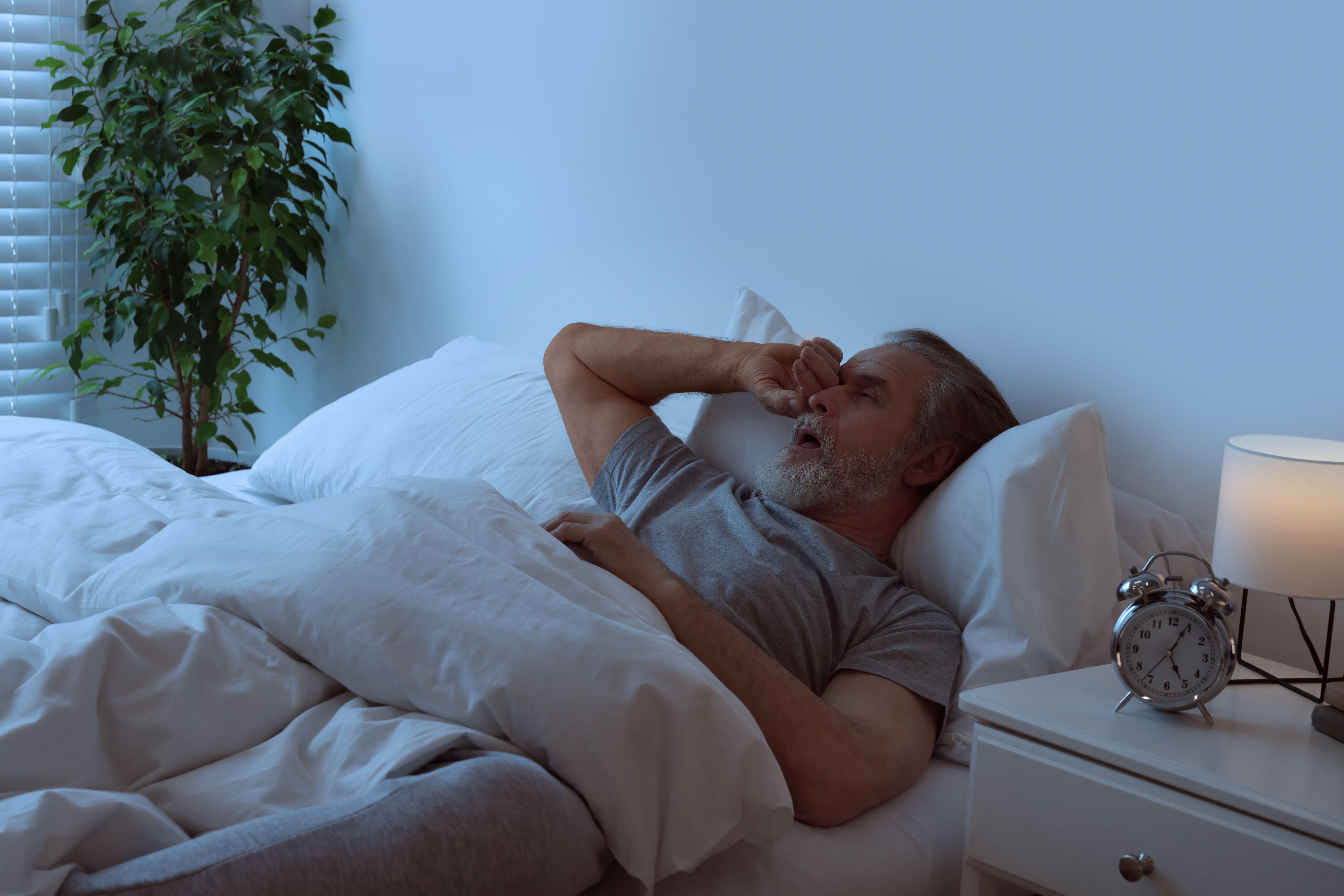 Man waking up in bed rubbing his dry eyes