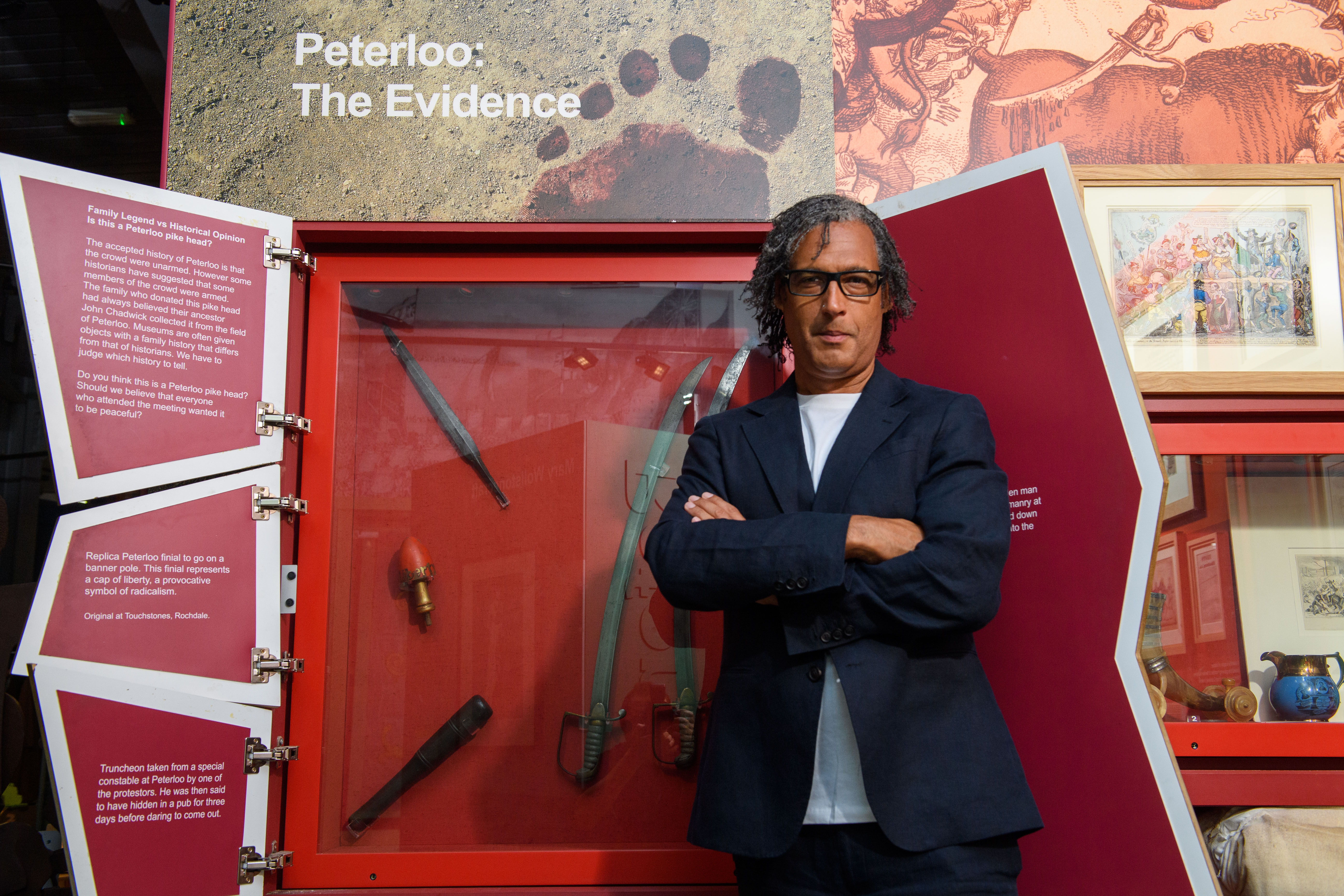 David Olusoga stands in front of a museum display on Peterloo