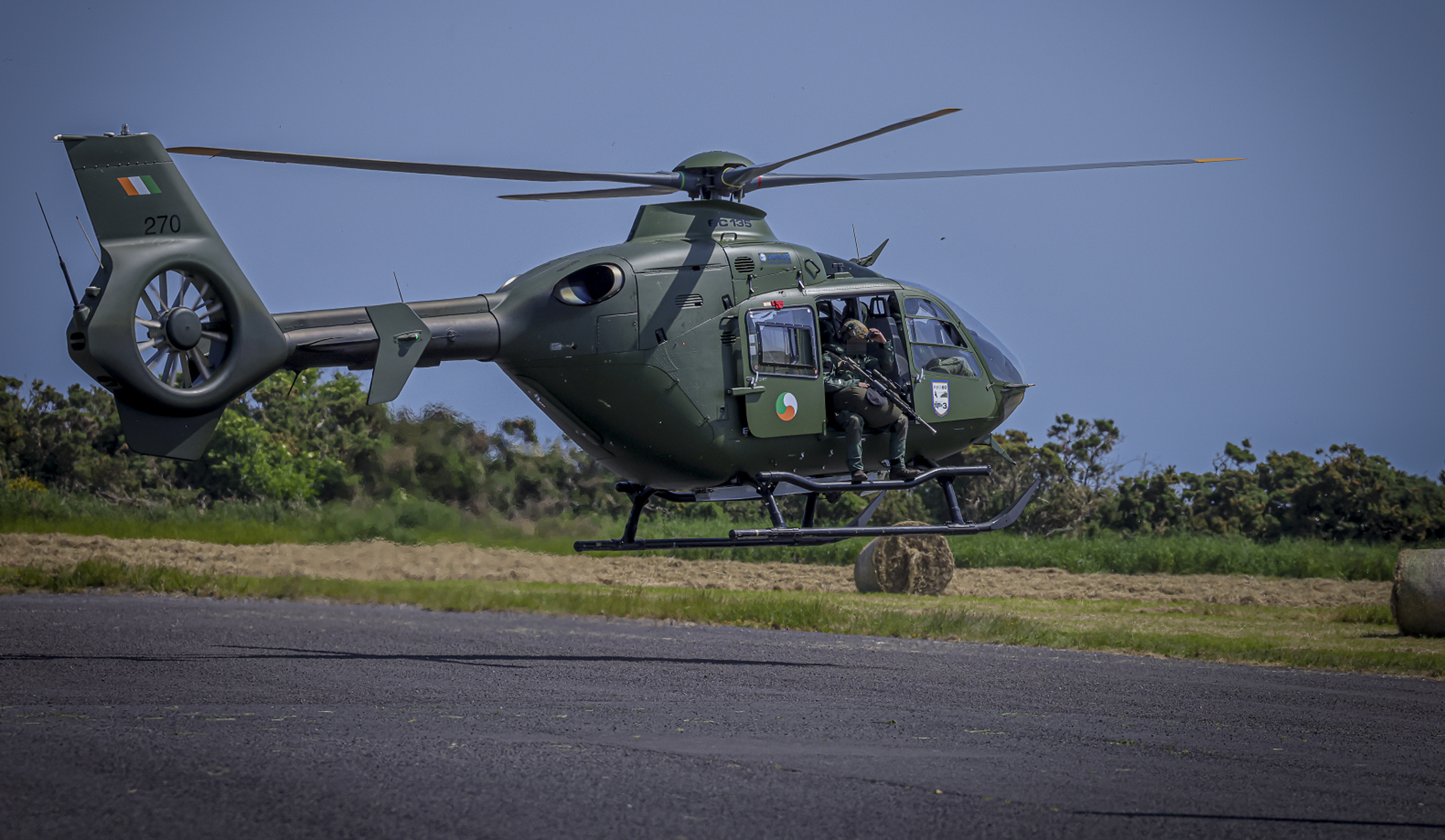 Armed soldiers on an Army helicopter just off the ground