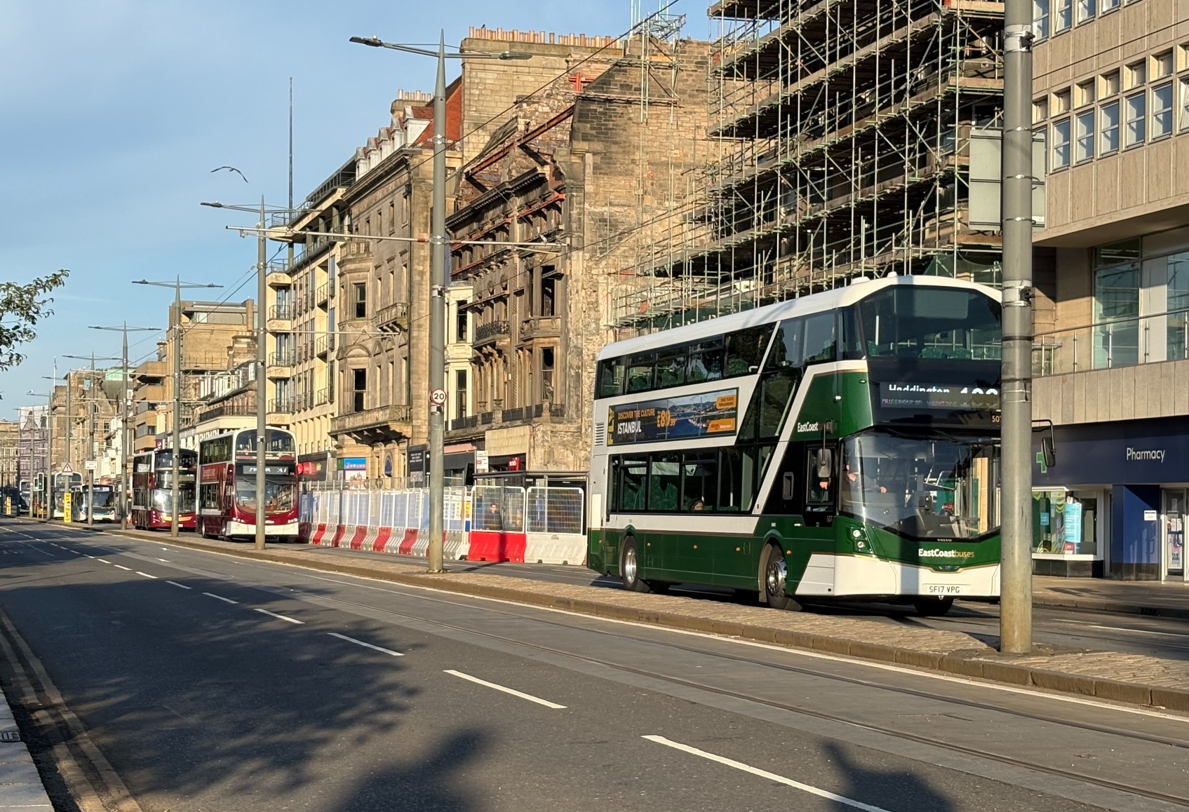 Buses travelling along Princes Street, with a fire-damaged building in the background