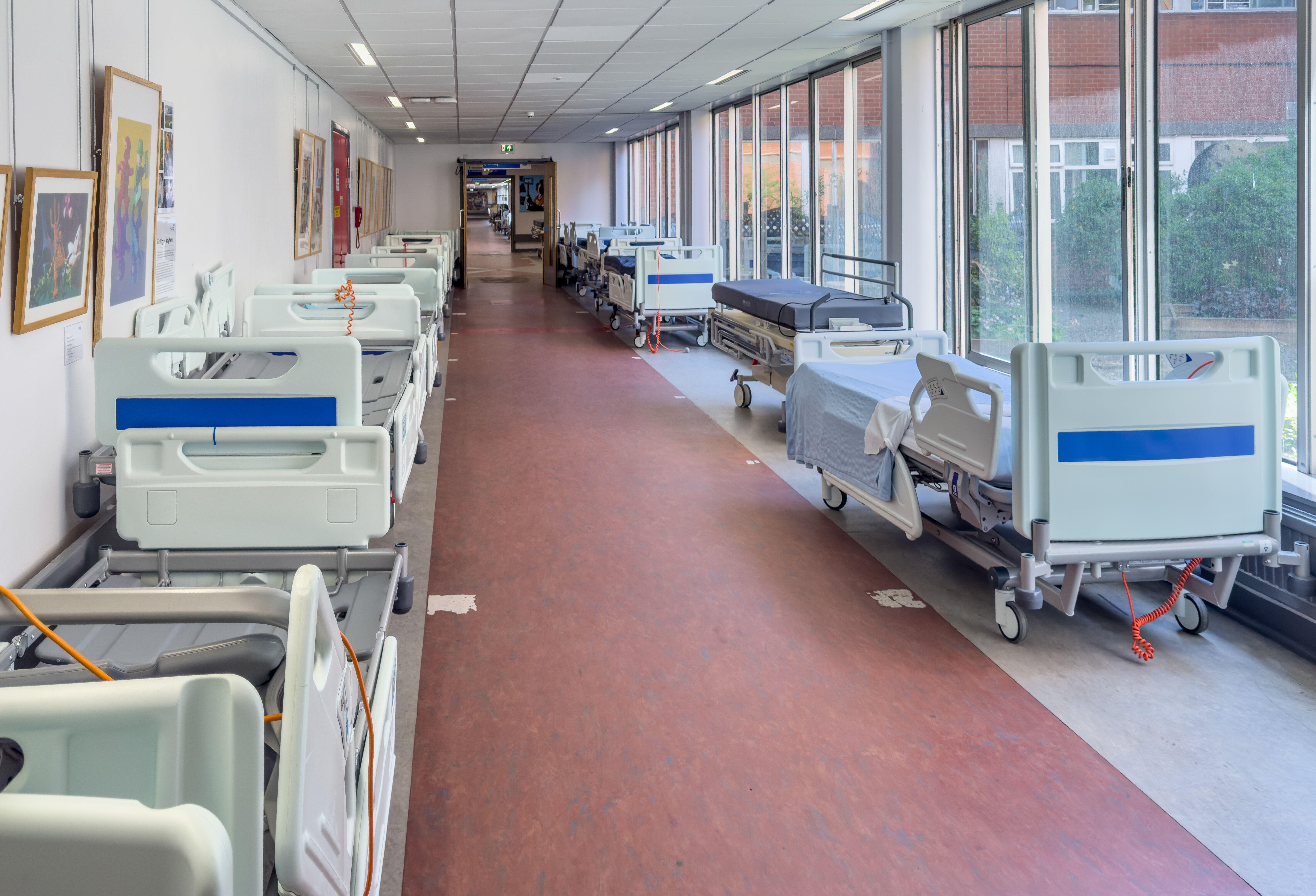 Empty beds lined up in a deserted hospital corridor