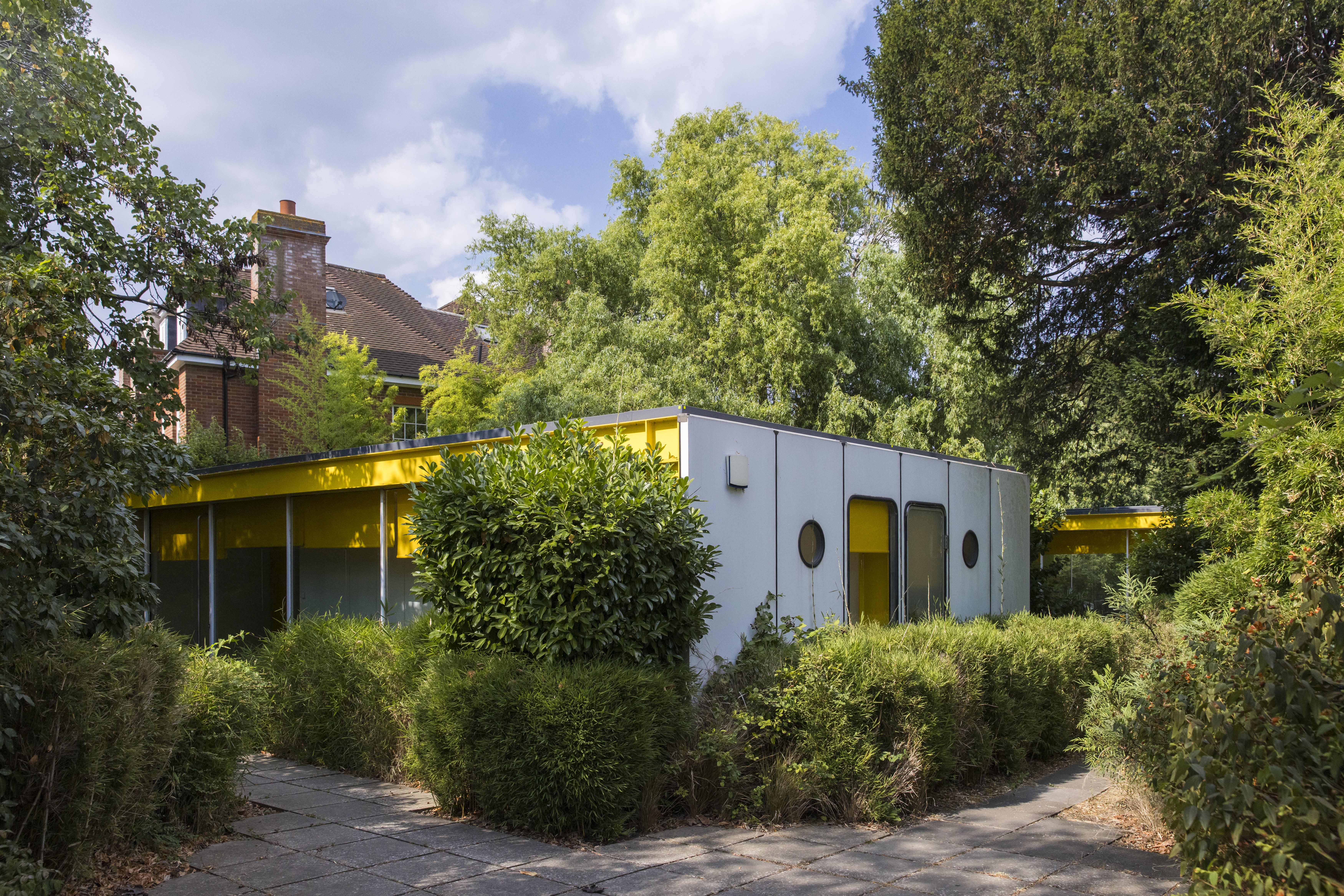 View of a small yellow-clad property amongst trees
