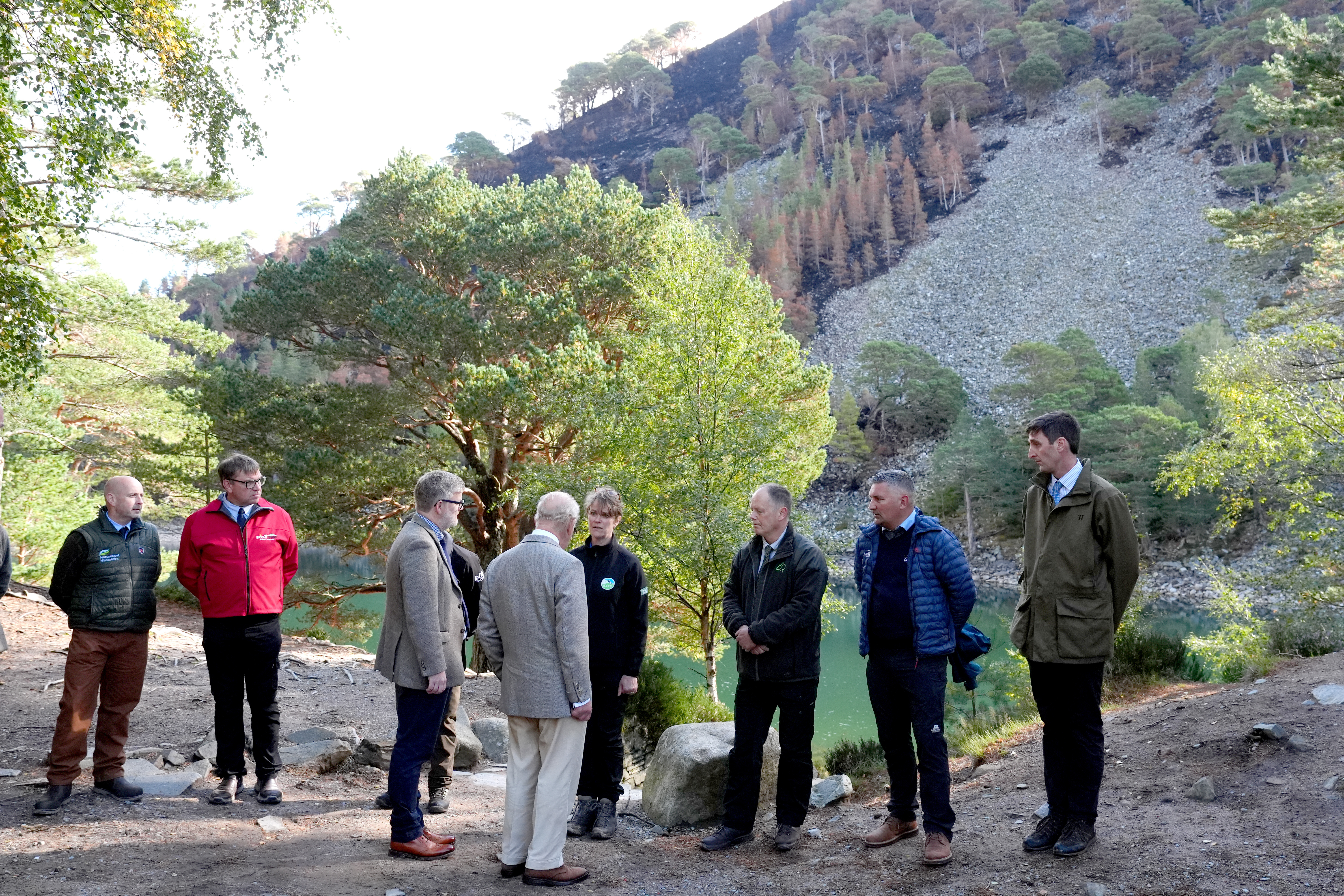 The King standing amongst a group in a woodland area above a loch