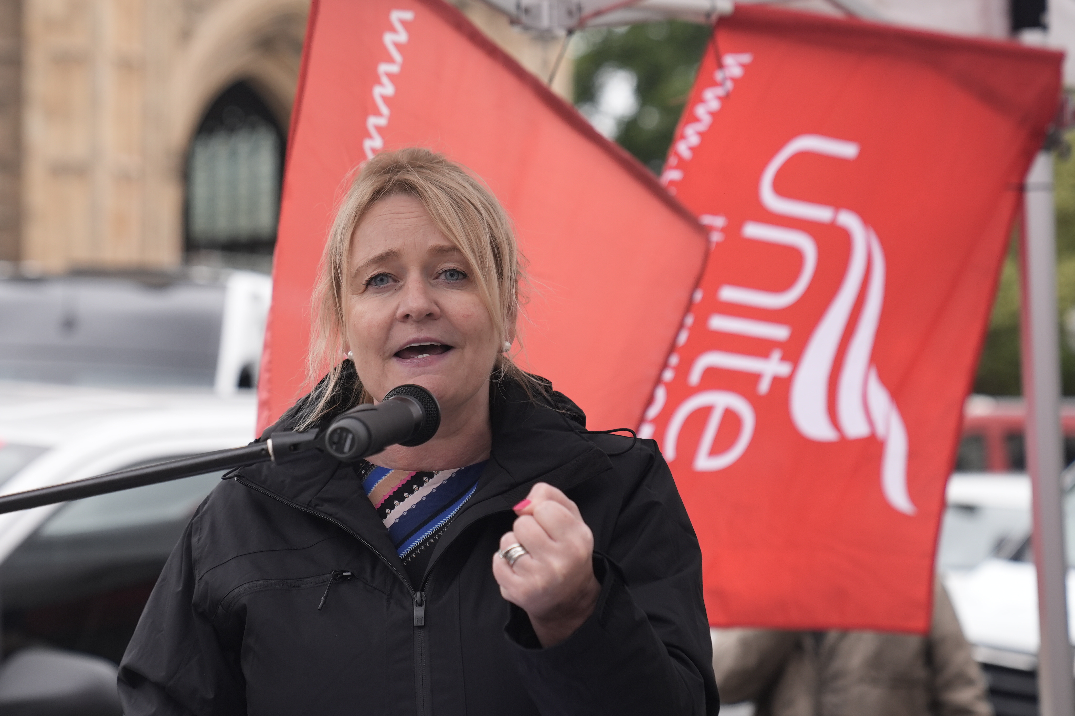 Sharon Graham speaking in front of Unite flags
