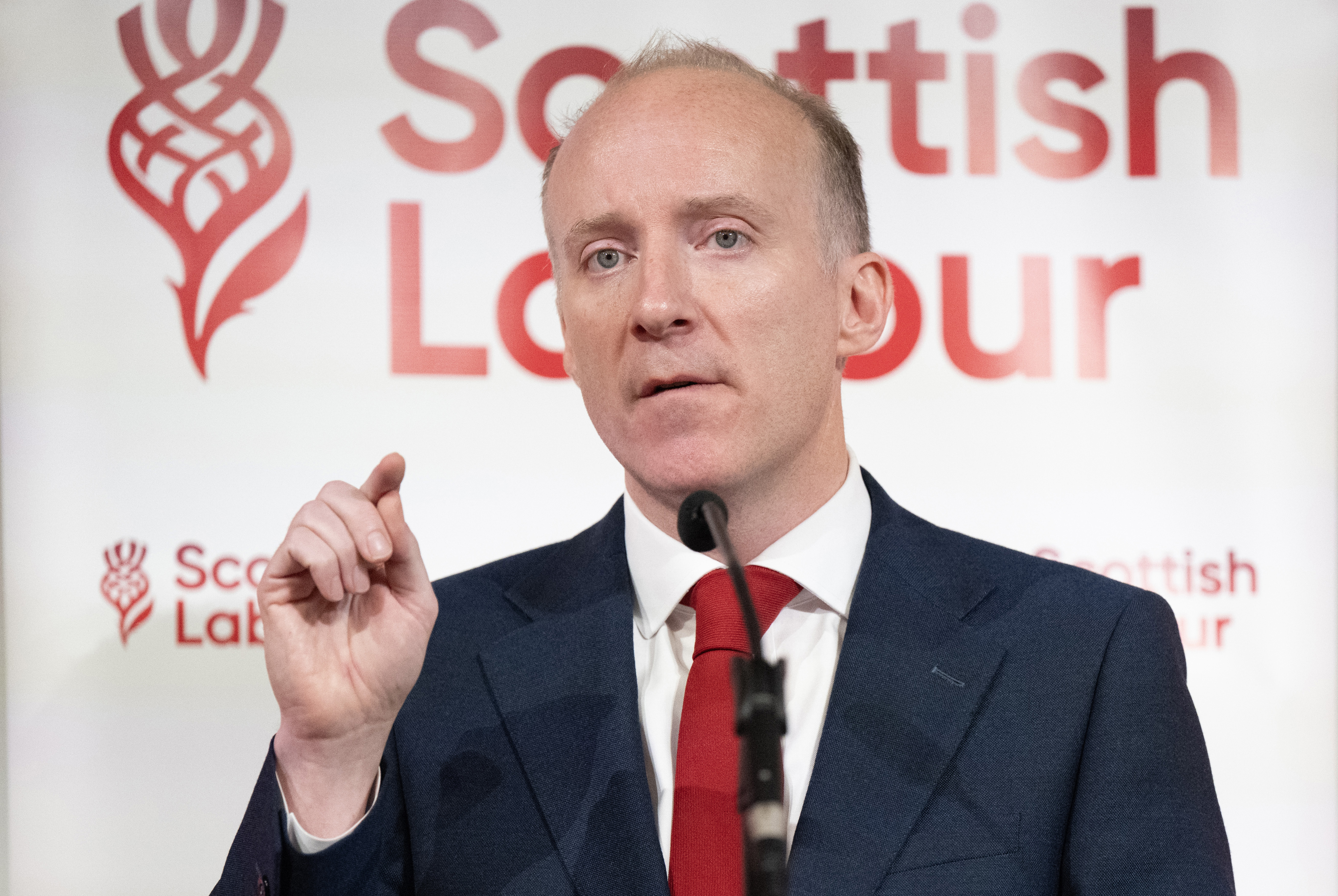 Head and shoulders photo of Michael Marra speaking, in front of Scottish Labour signage