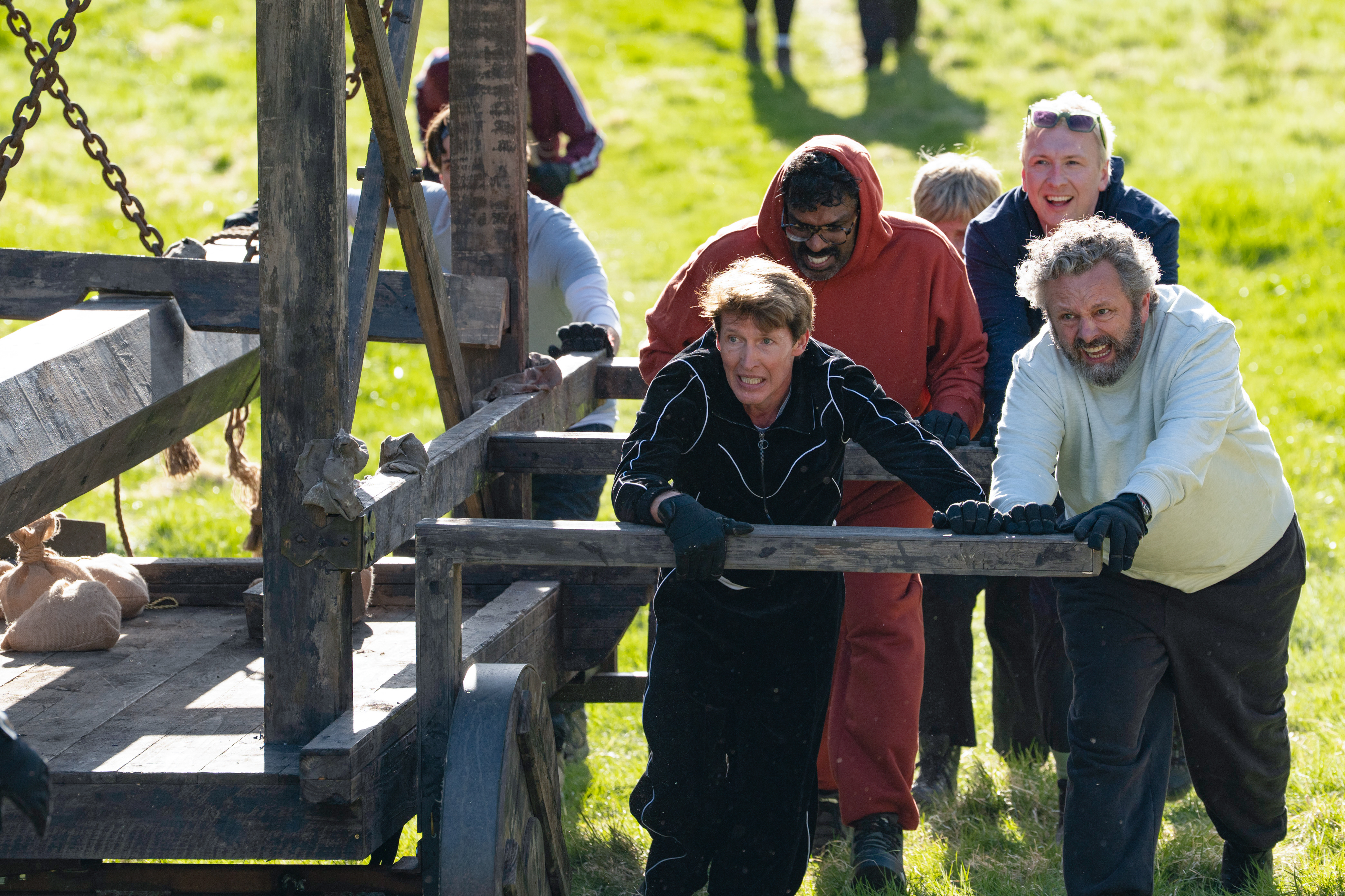 Celebrity Traitors contestants use a battering ram during a challenge