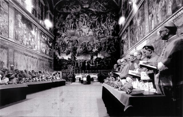 Cardinals stand in prayer inside the Sistine Chapel