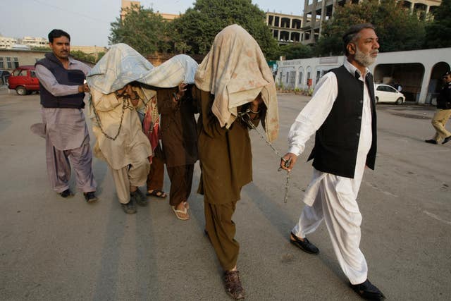 Pakistani security officials escort alleged militants of Tehreek-e-Taliban Pakistan to an anti-terrorist court in Karachi, Pakistan