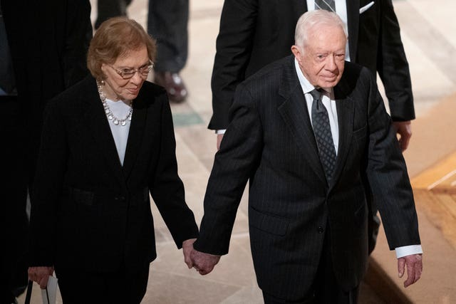 Mr Carter, right, and his wife, former first lady Rosalynn Carter, hold hands as they walk from a state funeral for former president George HW Bush at the National Cathedral in Washington in December 2018