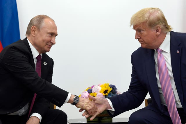 US President Donald Trump, right, shakes hands with Russian President Vladimir Putin