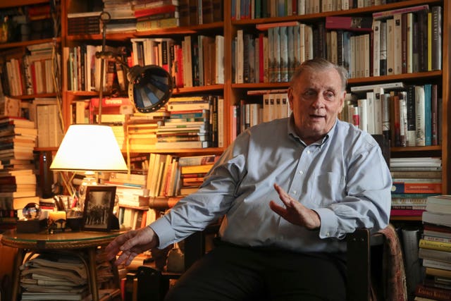 Edmund White with bookshelves behind him
