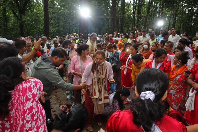 People gather to light candles and pray for the victims of flash floods at the site of a mass burial in Chitwan, Nepal,