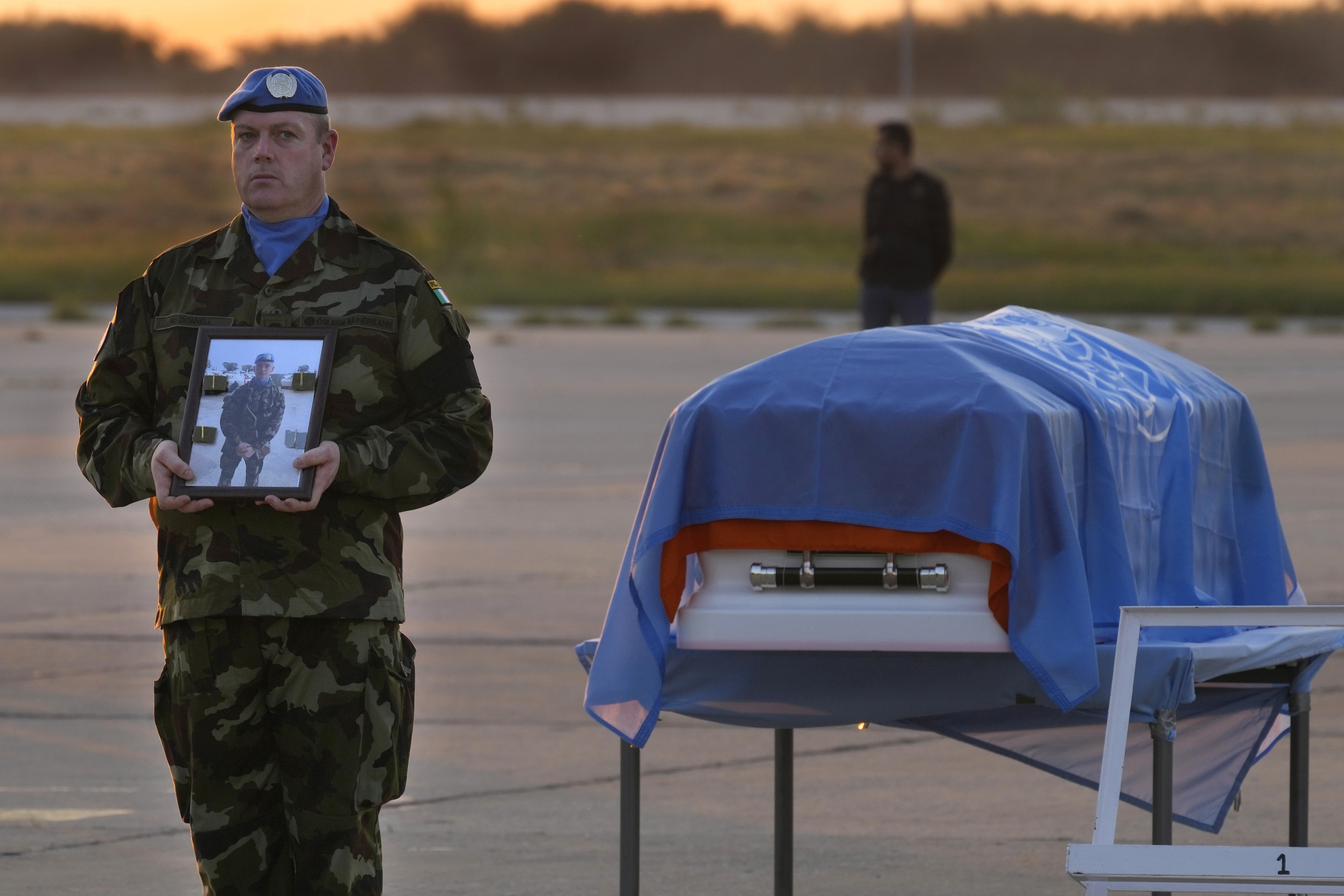 An Irish UN peacekeeper stands next to the coffin of his comrade Sean Rooney