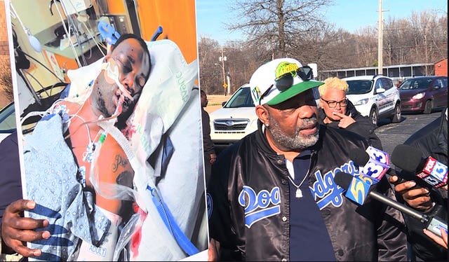 Tyre Nichols’ stepfather Rodney Wells, right, holds a photo of Nichols in the hospital after his arrest