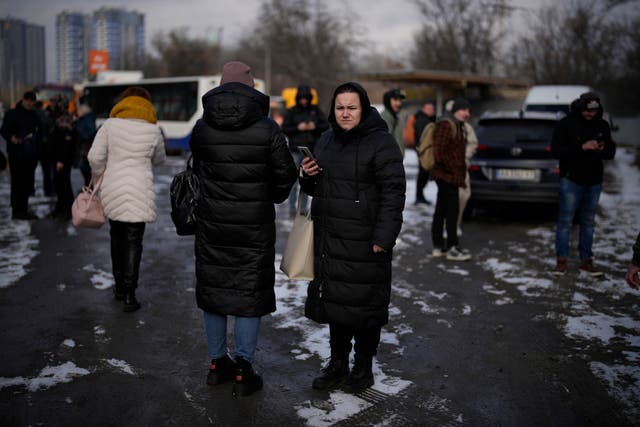People wait on a street blocked by police after a rocket attack in Kyiv, Ukraine
