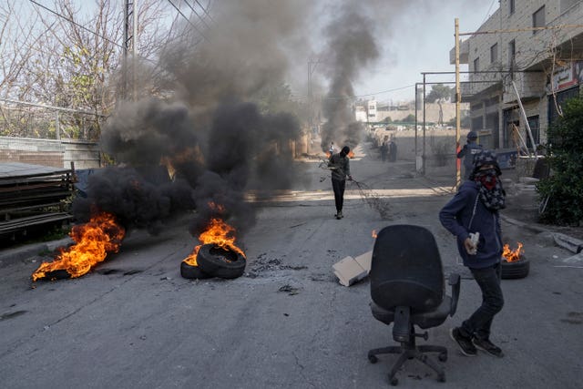 Masked Palestinian demonstrators burn tyres in a protest against a deadly Israeli army raid at Aida Refugee camp, in the West Bank city of Bethlehem