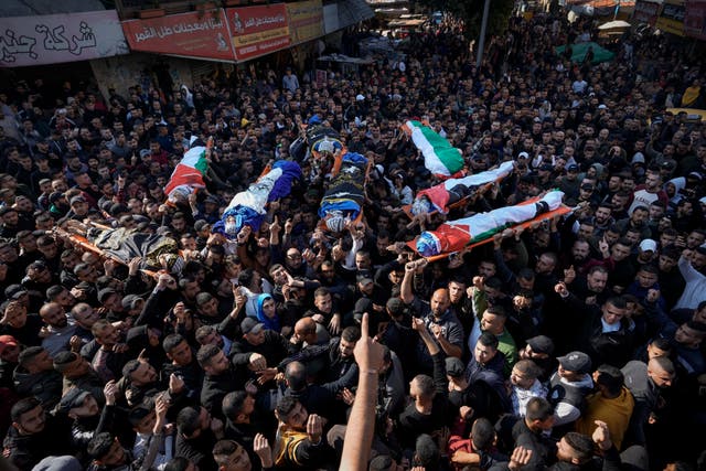 Mourners carry the bodies of eight Palestinians, some draped in the flag of the Islamic Jihad militant group, during a joint funeral in the West Bank city of Jenin on Thursday