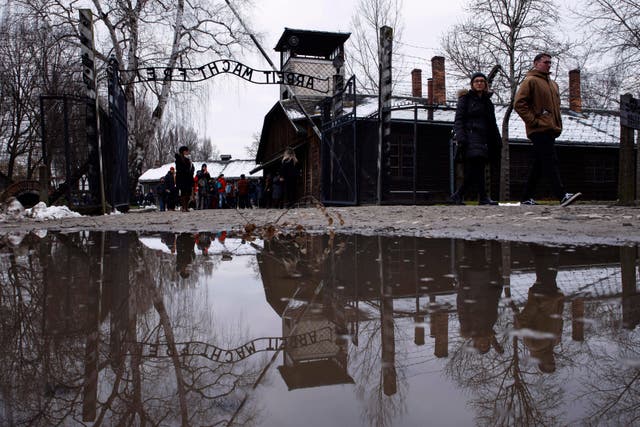People walk next to the 'Arbeit Macht Frei' (Work Sets You Free) gate at the former Nazi German concentration and extermination camp Auschwitz-Birkenau in Oswiecim, Poland