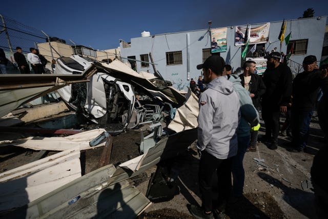 Palestinians inspect the site of a damaged building following an Israeli forces raid in the West Bank city of Jenin
