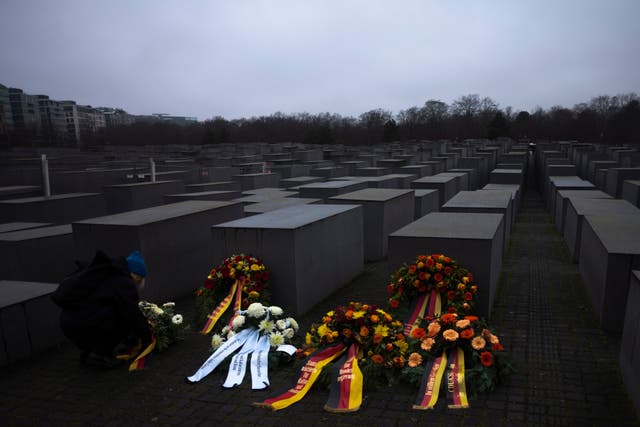 A woman adjusts a wreath placed at the Memorial to the Murdered Jews of Europe on the International Holocaust Remembrance Day in Berlin, Germany