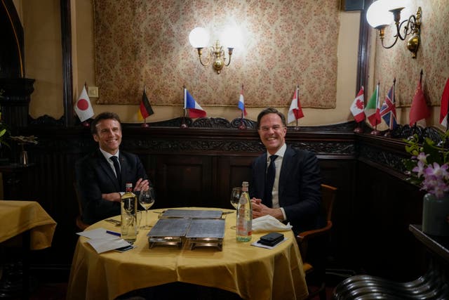 French President Emmanuel Macron, left, and Dutch Prime Minister Mark Rutte, right, pose for the media in a restaurant in The Hague, Netherlands