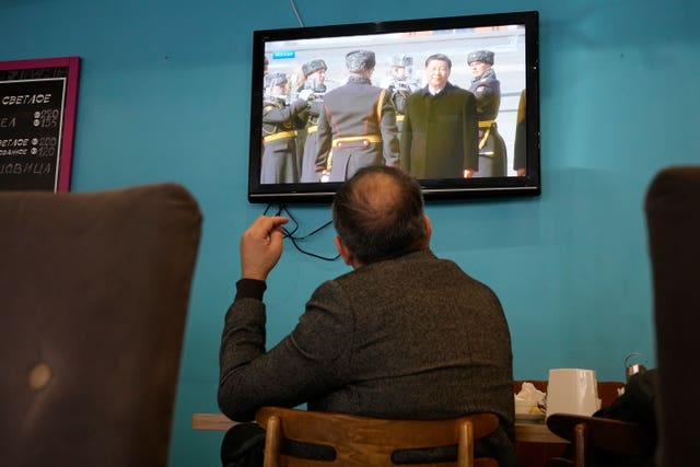A TV screen displays Chinese President Xi Jinping attending an official welcome ceremony upon his arrival at the Vnukovo-2 government airport outside Moscow, in a cafe in St Petersburg, Russia