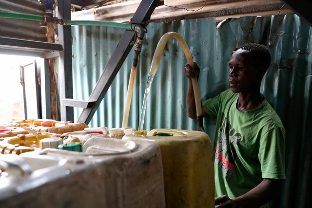 A man fills cans with water from a water tank vendor in Nairobi, Kenya
