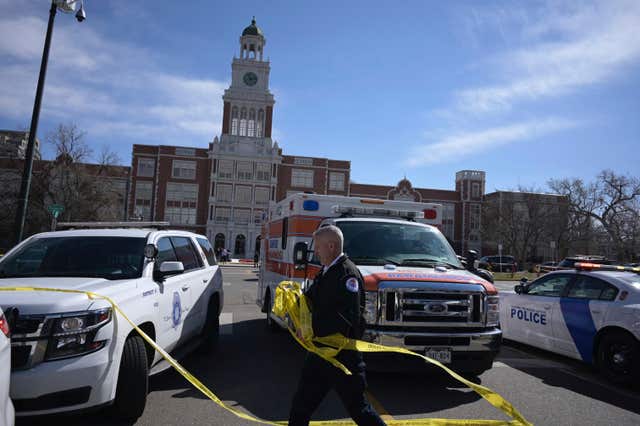 Emergency personnel remove police tape from outside the school