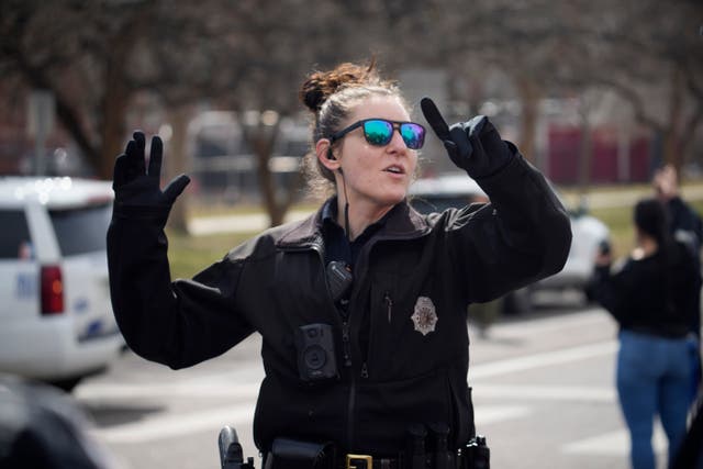 A Denver Police officer directs parents to meet their children after the shooting