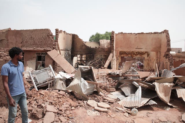 A man walks by a house hit in recent fighting in Khartoum