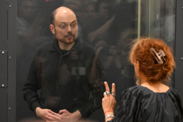 Russian opposition activist Vladimir Kara-Murza speaks with his lawyer standing in a glass cage in a courtroom during announcement of the verdict on appeal at Moscow City Court